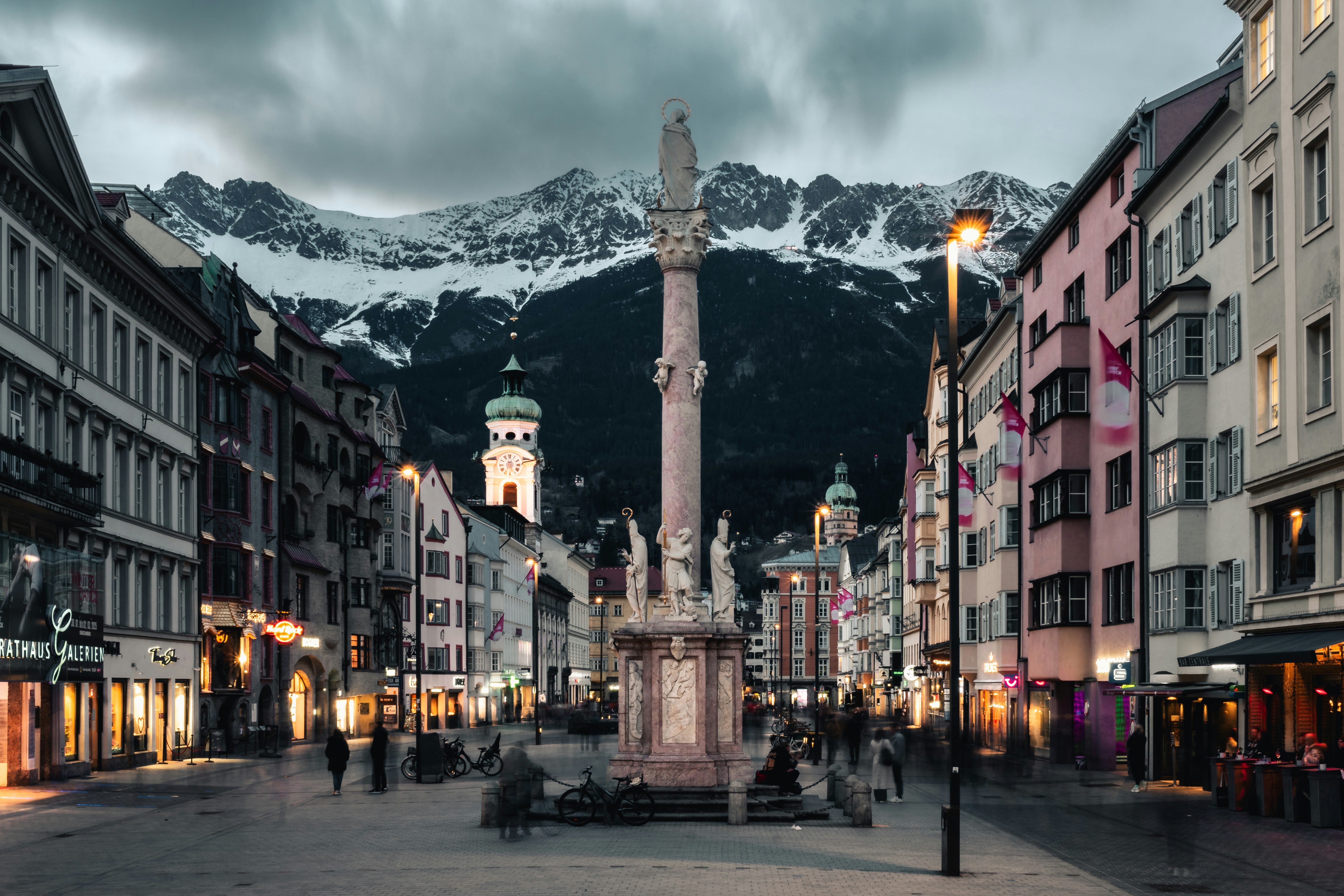 Una plaza del pueblo con una fuente y montañas al fondo