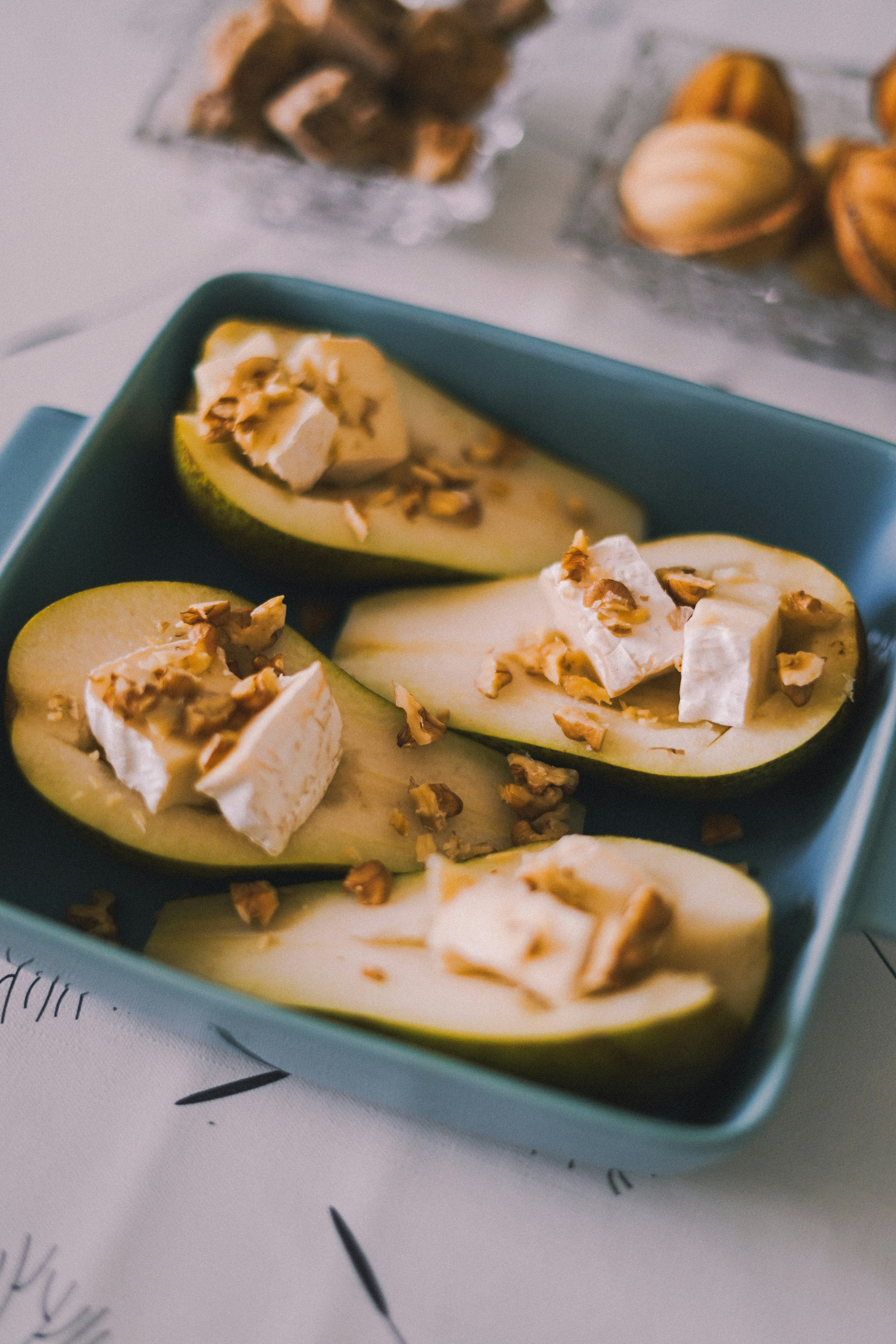 A blue dish filled with sliced apples and nuts