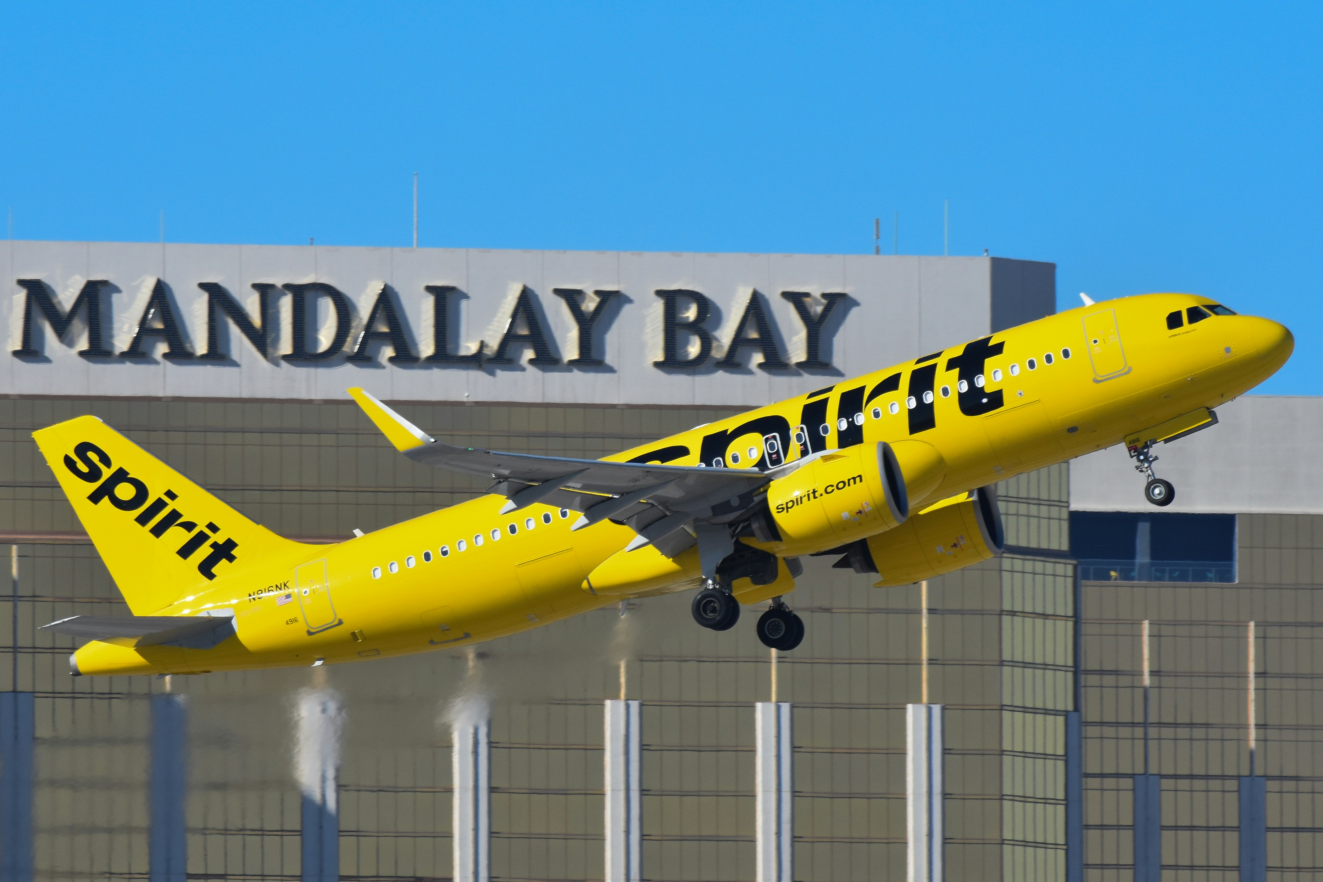 A yellow and black jet airliner taking off from an airport