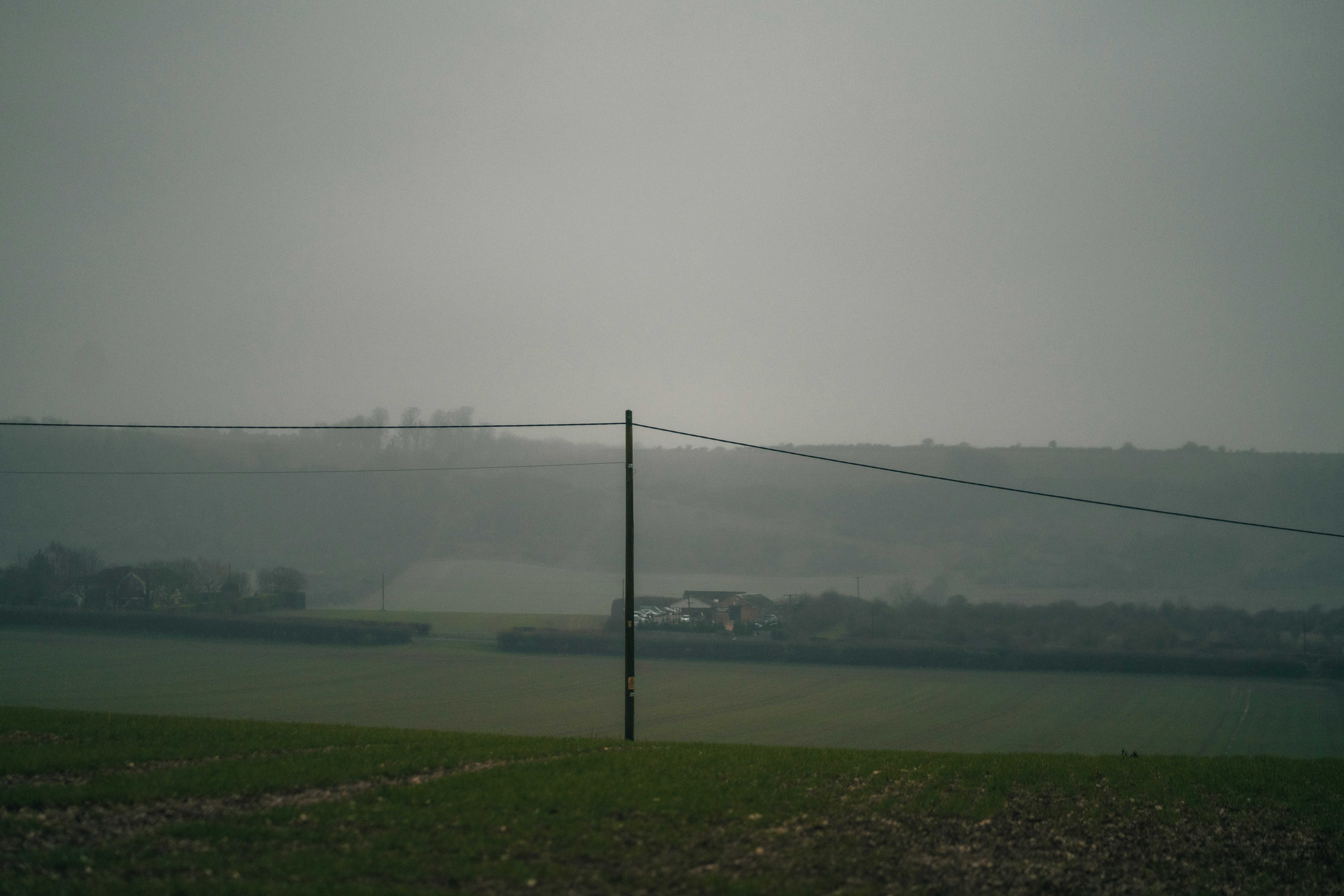 Un campo brumoso con un poste de teléfono en primer plano