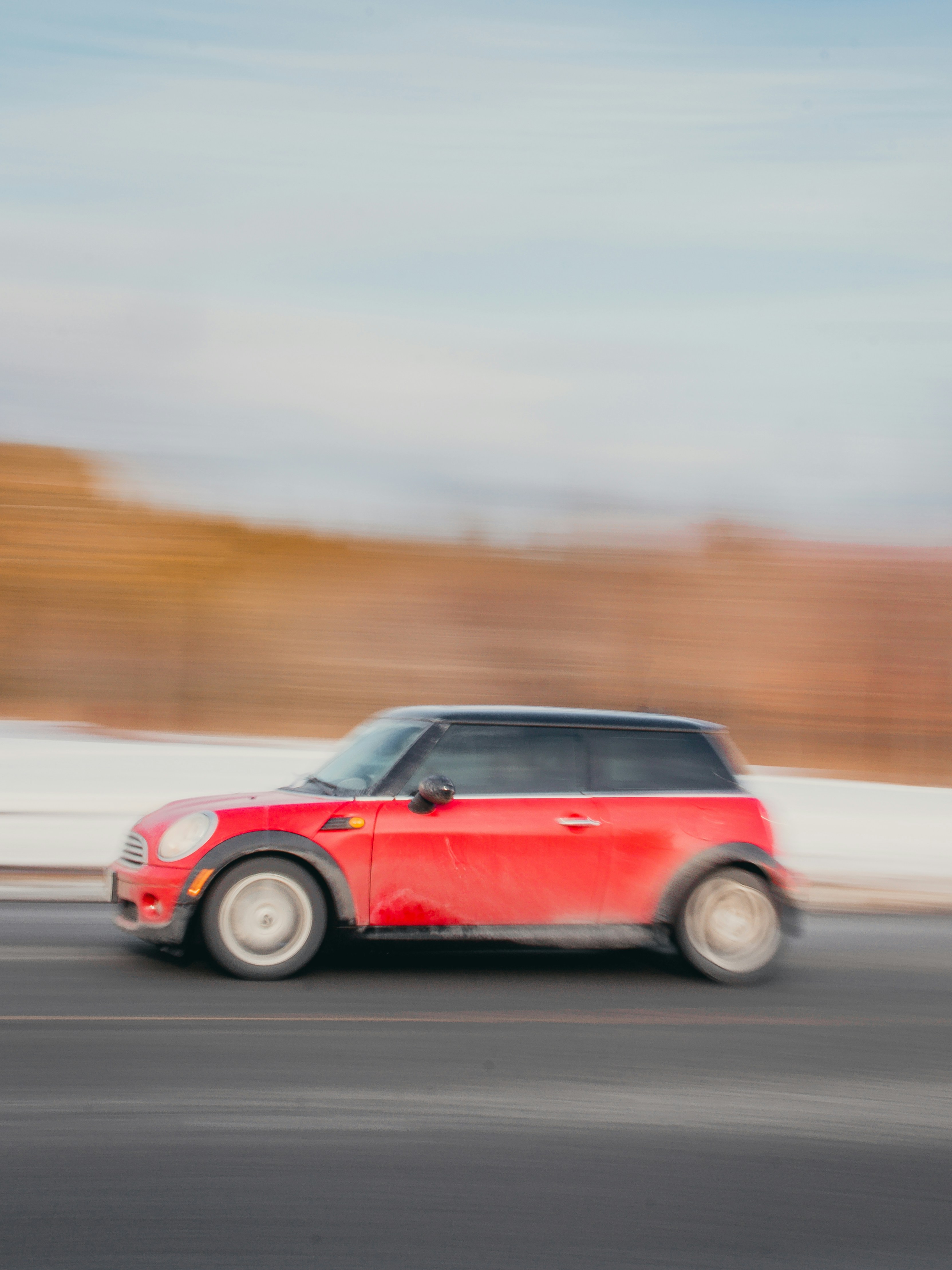 A red minivan driving down a street