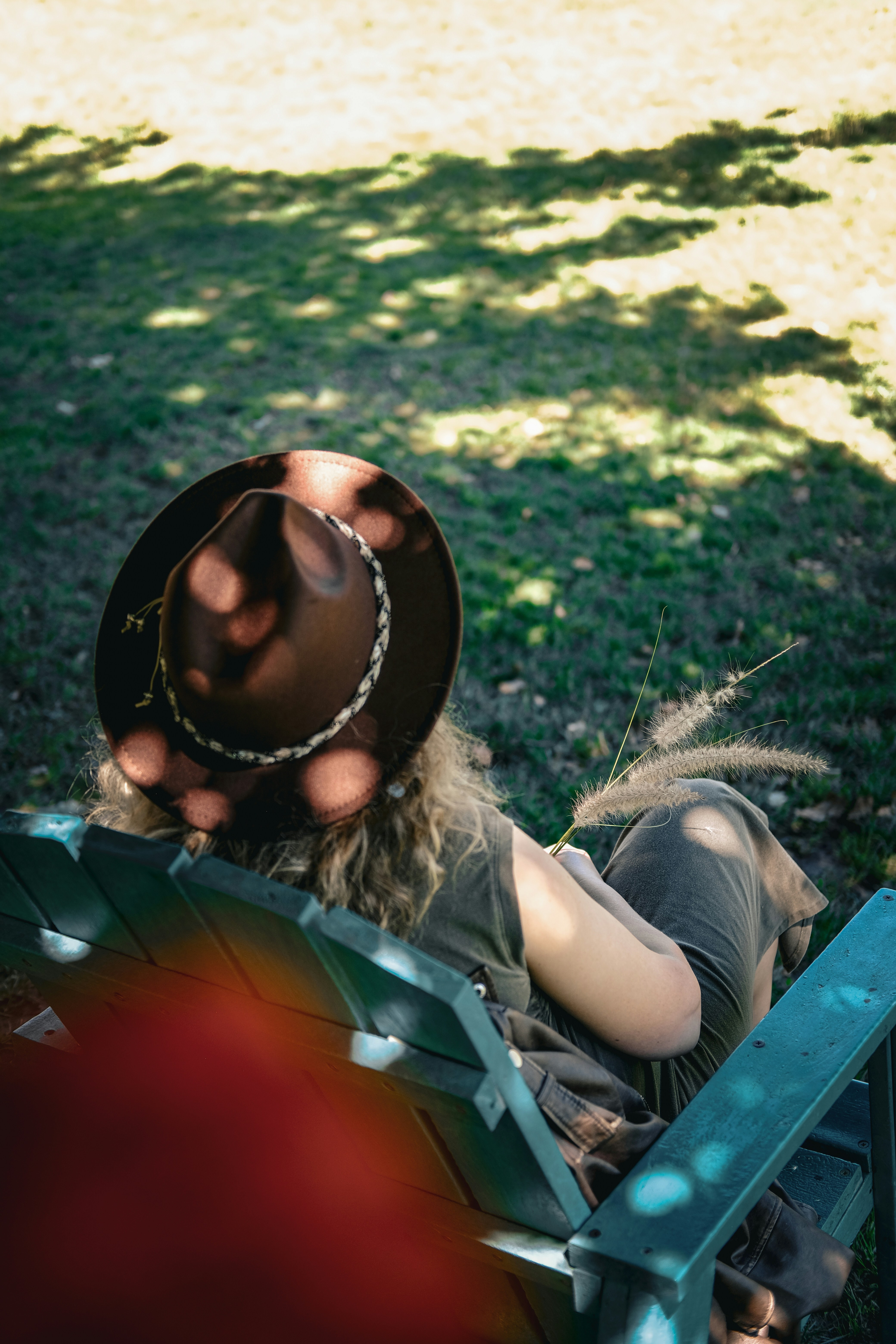 A woman wearing a cowboy hat sitting on a bench