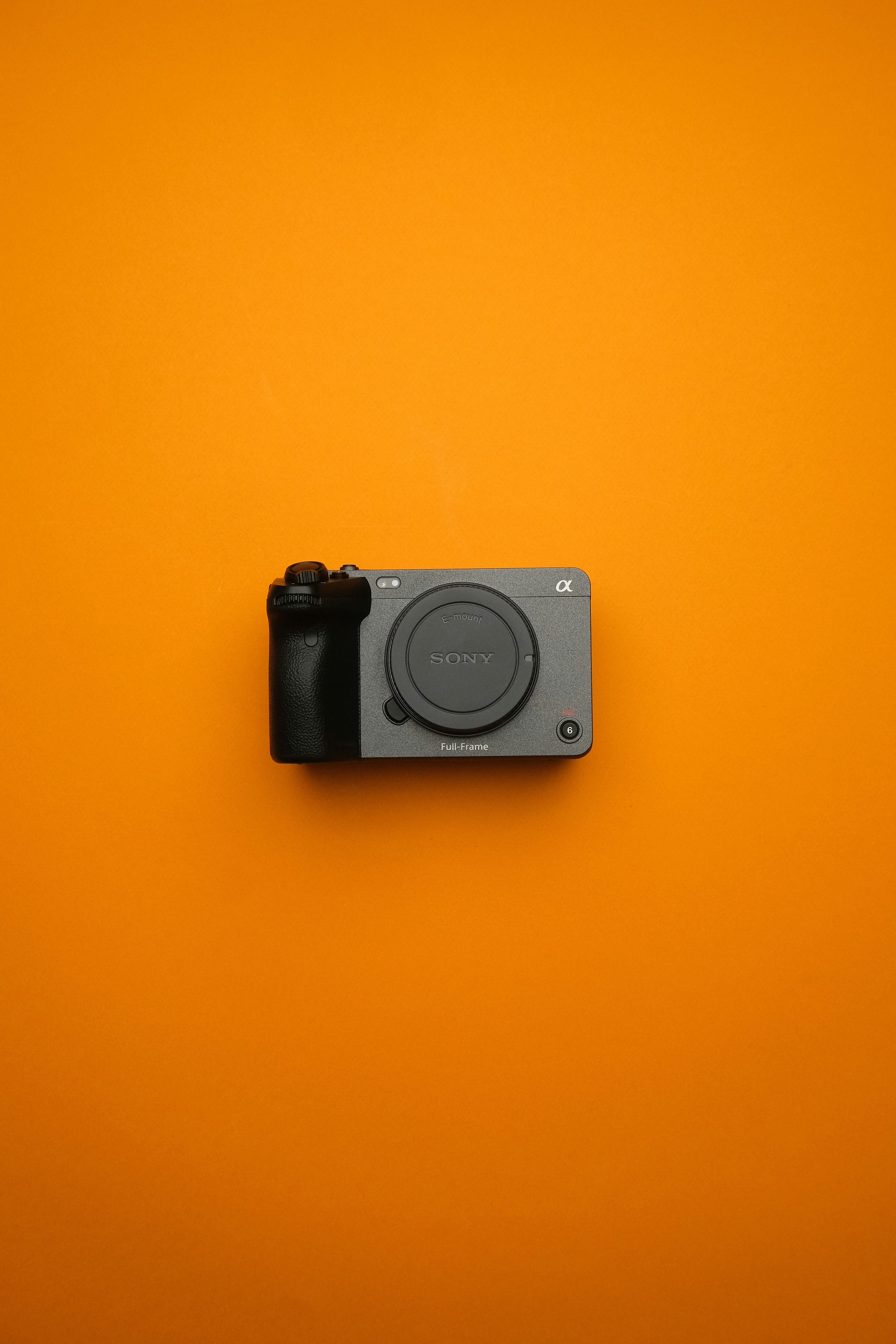 A camera mounted on a wall with an orange background
