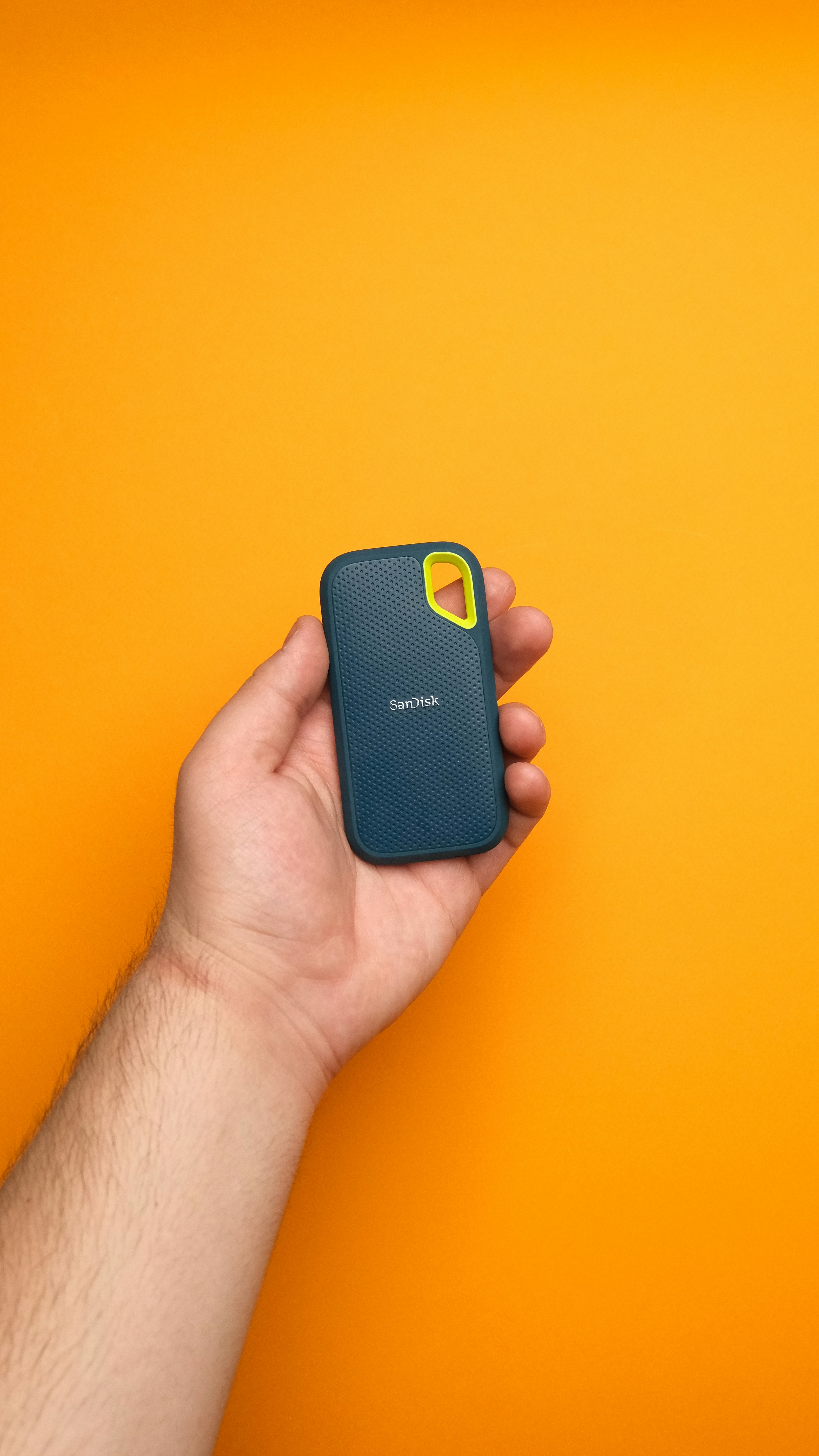 A hand holding a cell phone against a yellow background
