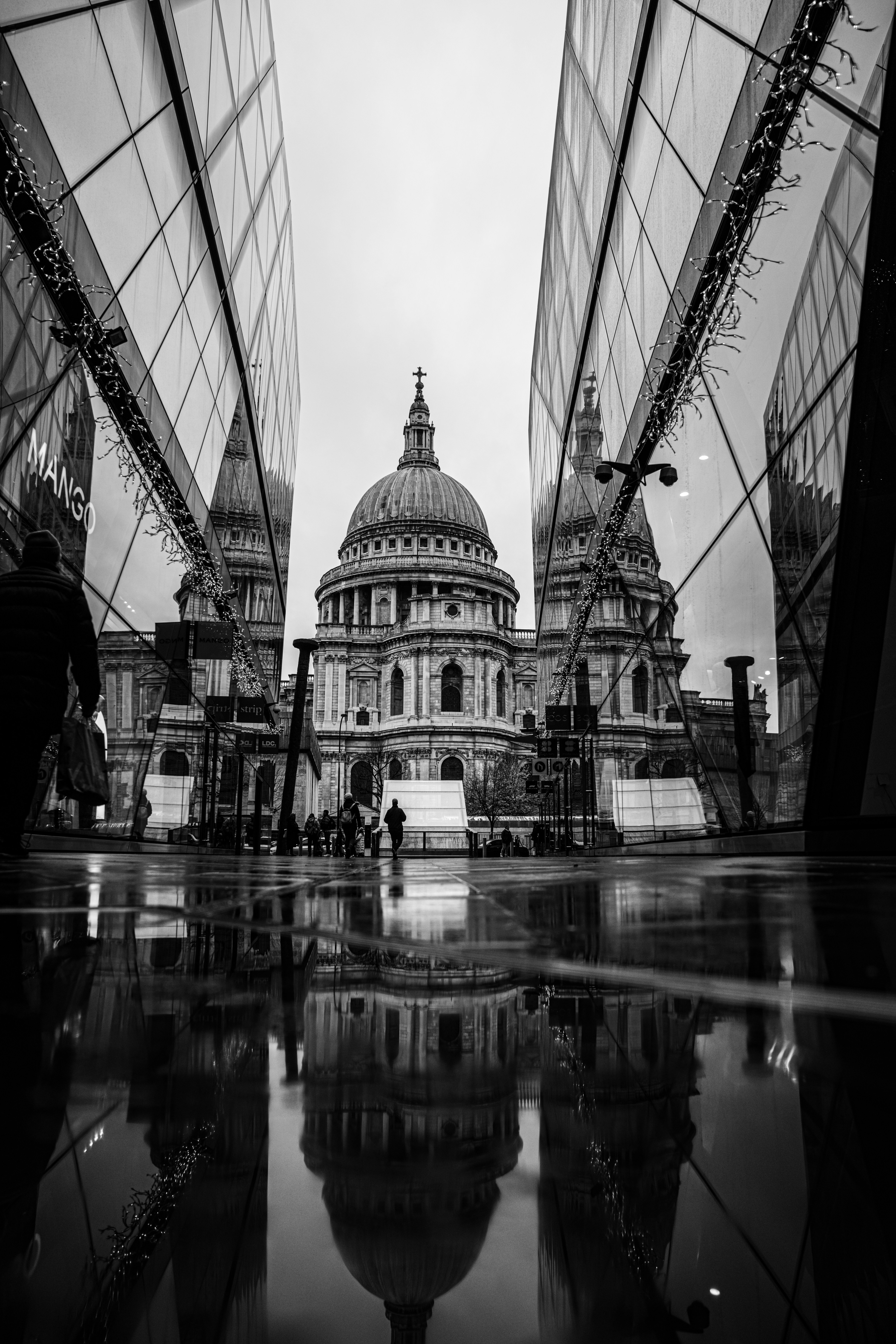 A black and white photo of a building and its reflection