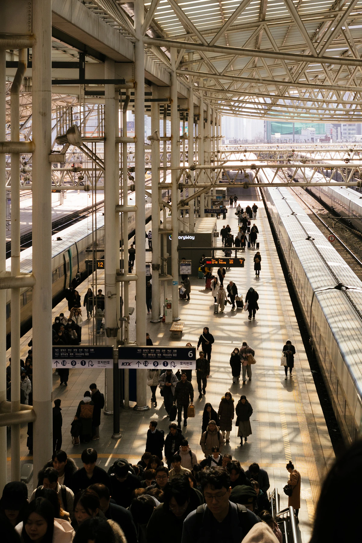 Travellers walking a busy Seoul Station platform under KTX signage