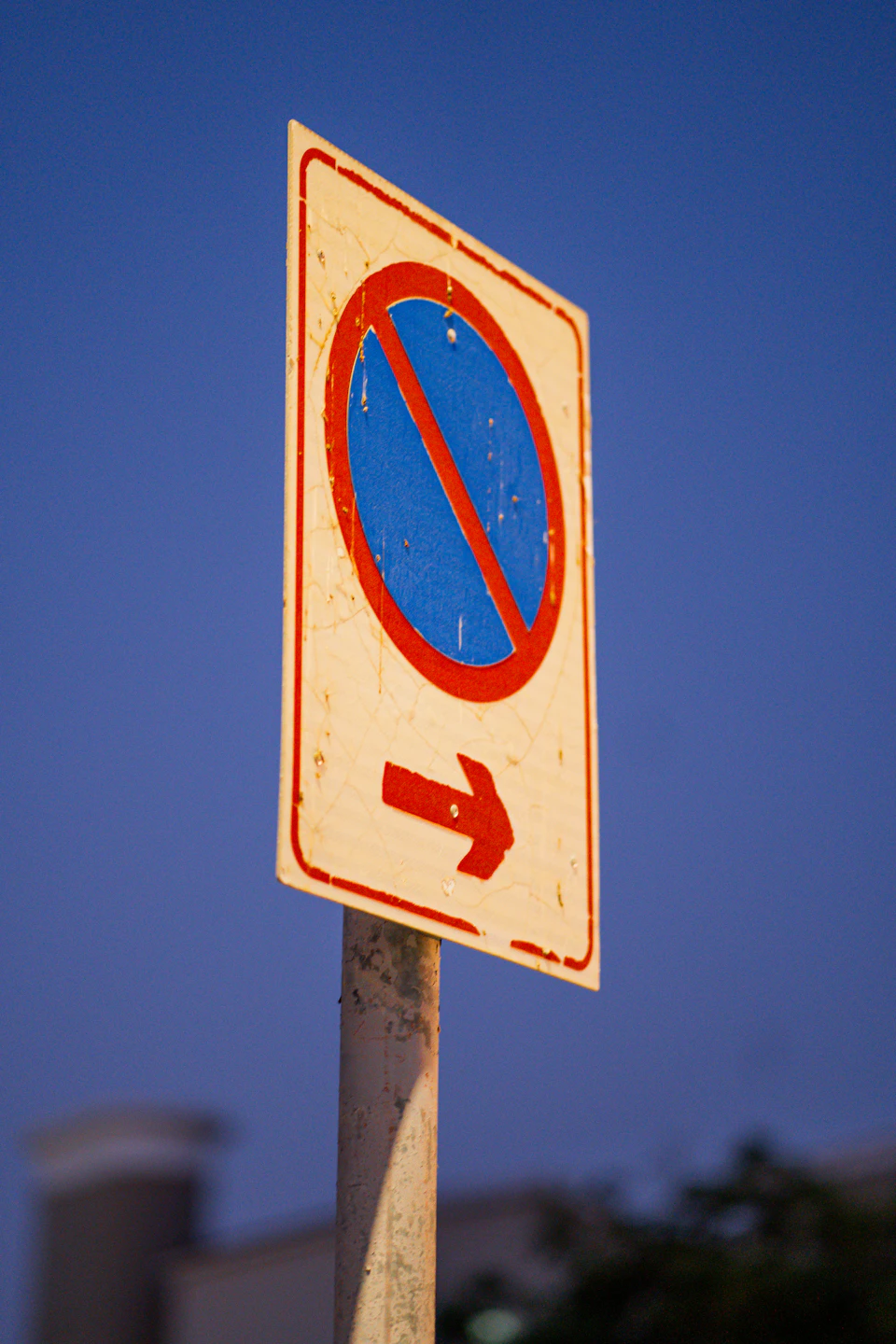 Street sign mounted on metal pole against clear blue sky backdrop features red border