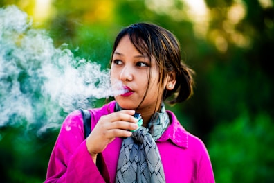 A woman in a pink shirt is smoking a cigarette