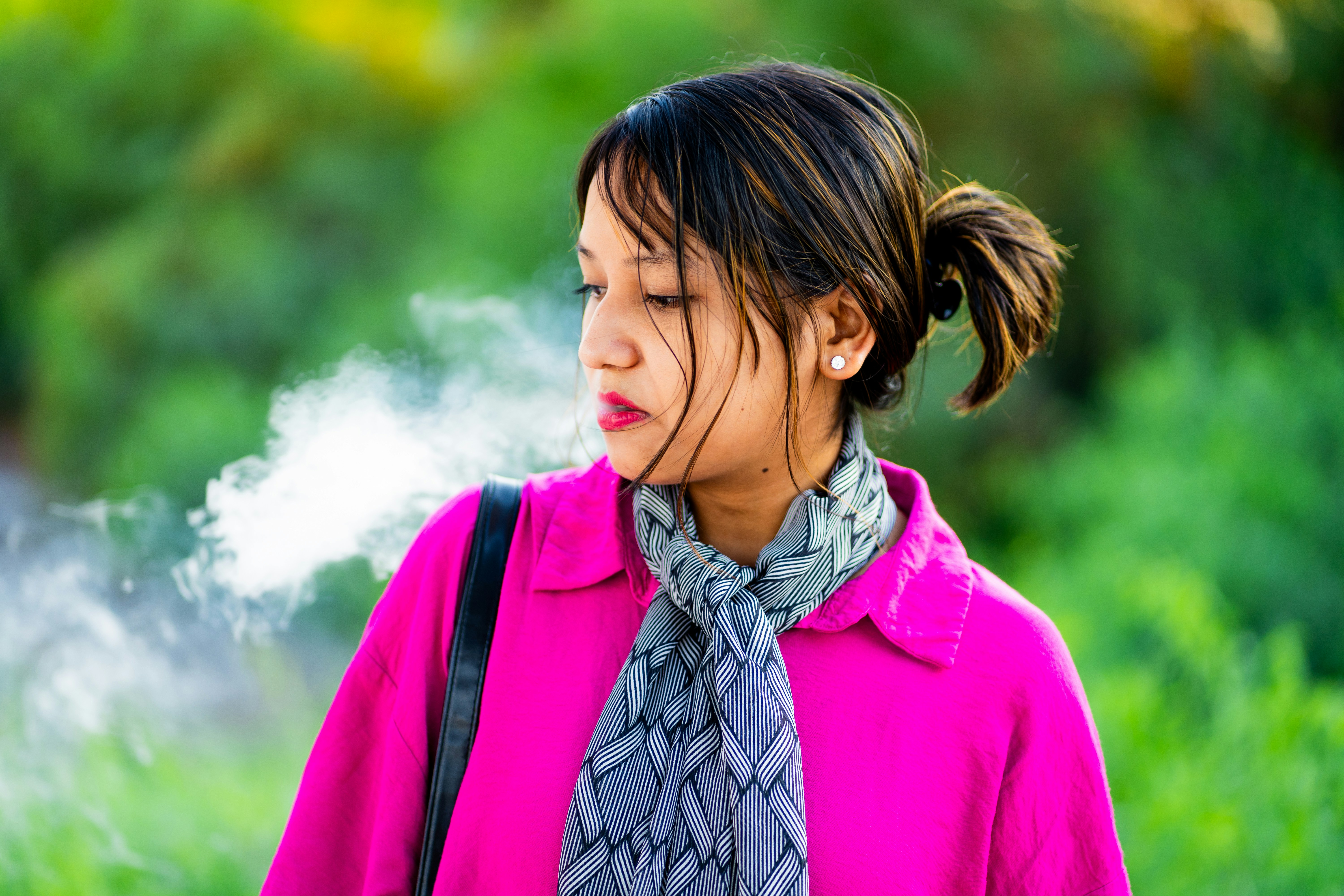 A woman in a pink jacket smoking a cigarette