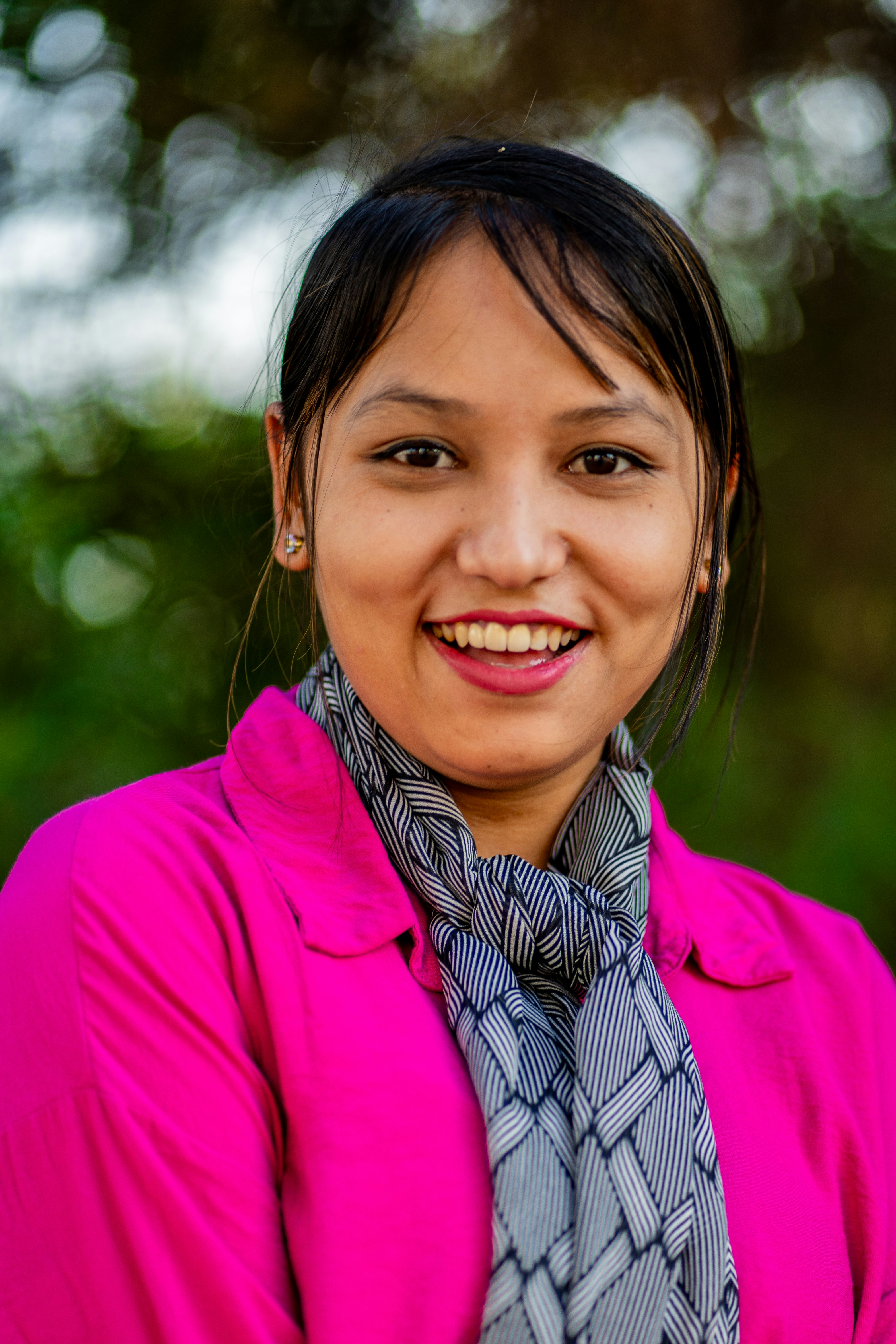 A woman in a pink jacket and scarf smiling
