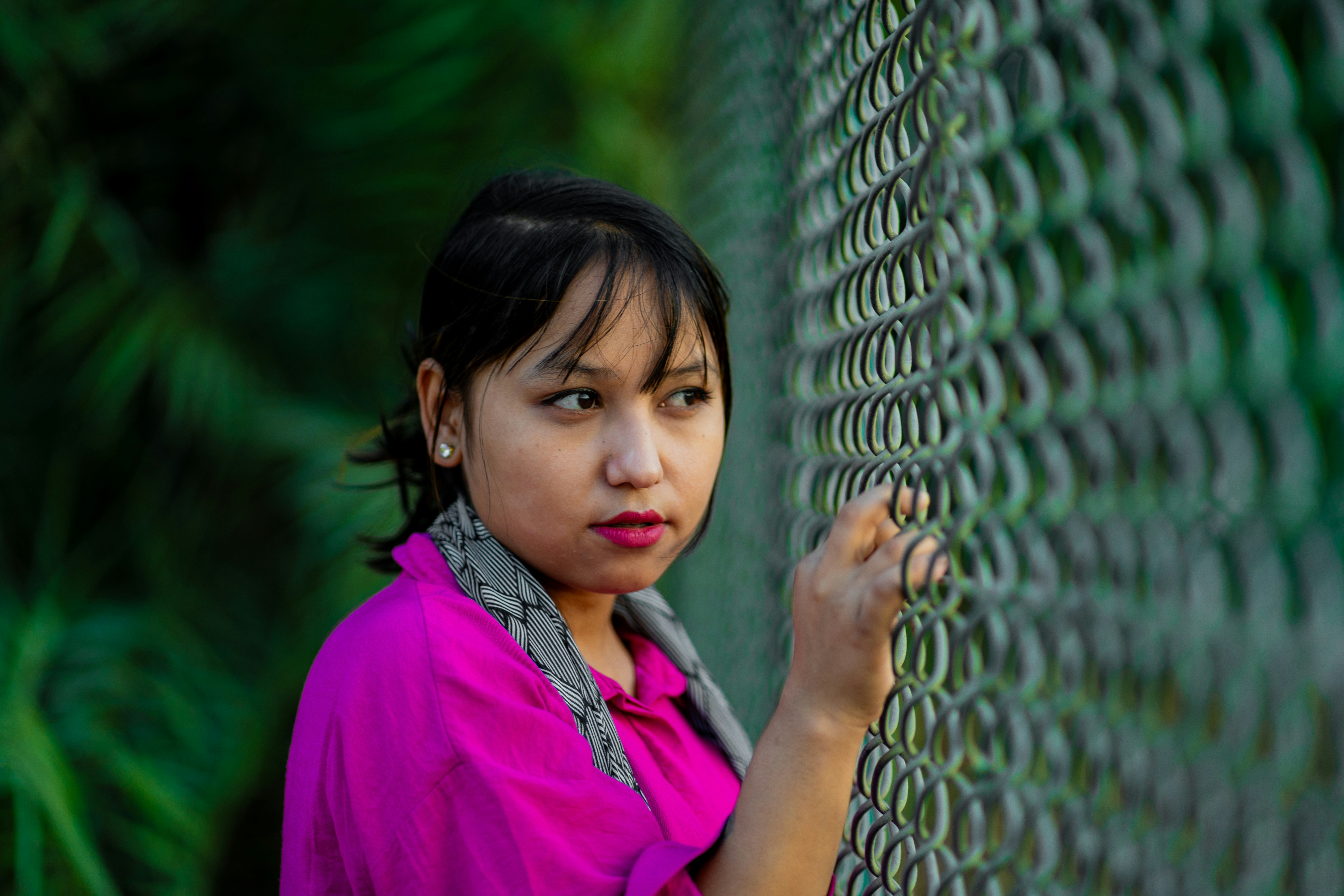 A young girl leaning against a chain link fence