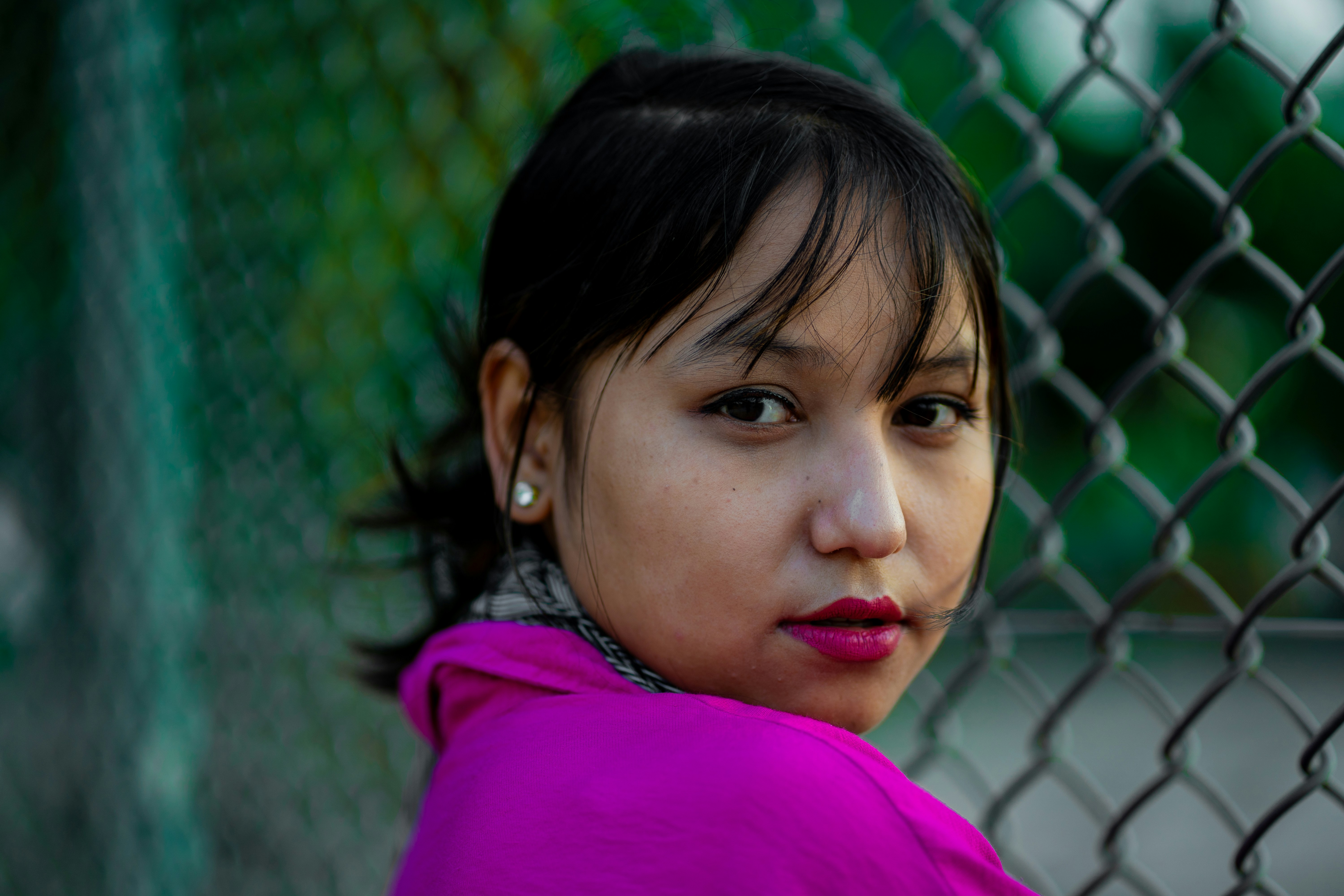 A woman leaning against a fence wearing a purple jacket