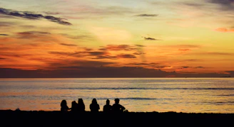 A group of people sitting on top of a sandy beach