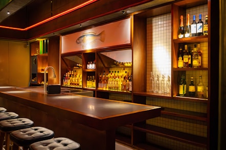 A bar with stools and bottles on the shelves