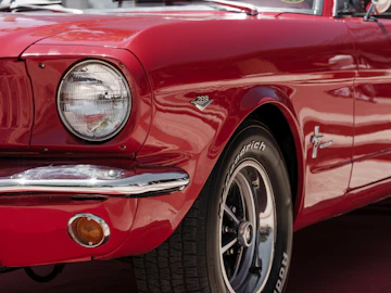 A close up of the front of a red mustang
