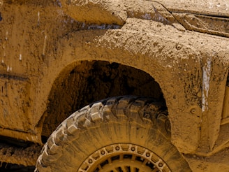 A close up of a yellow truck with mud on it