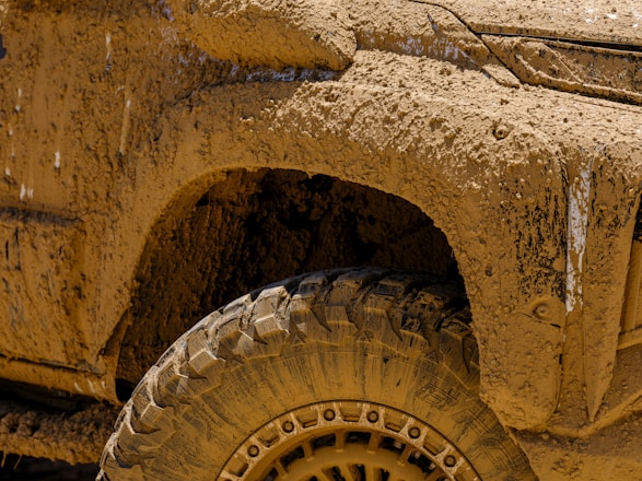 A close up of a yellow truck with mud on it