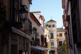A narrow city street with a clock tower in the background