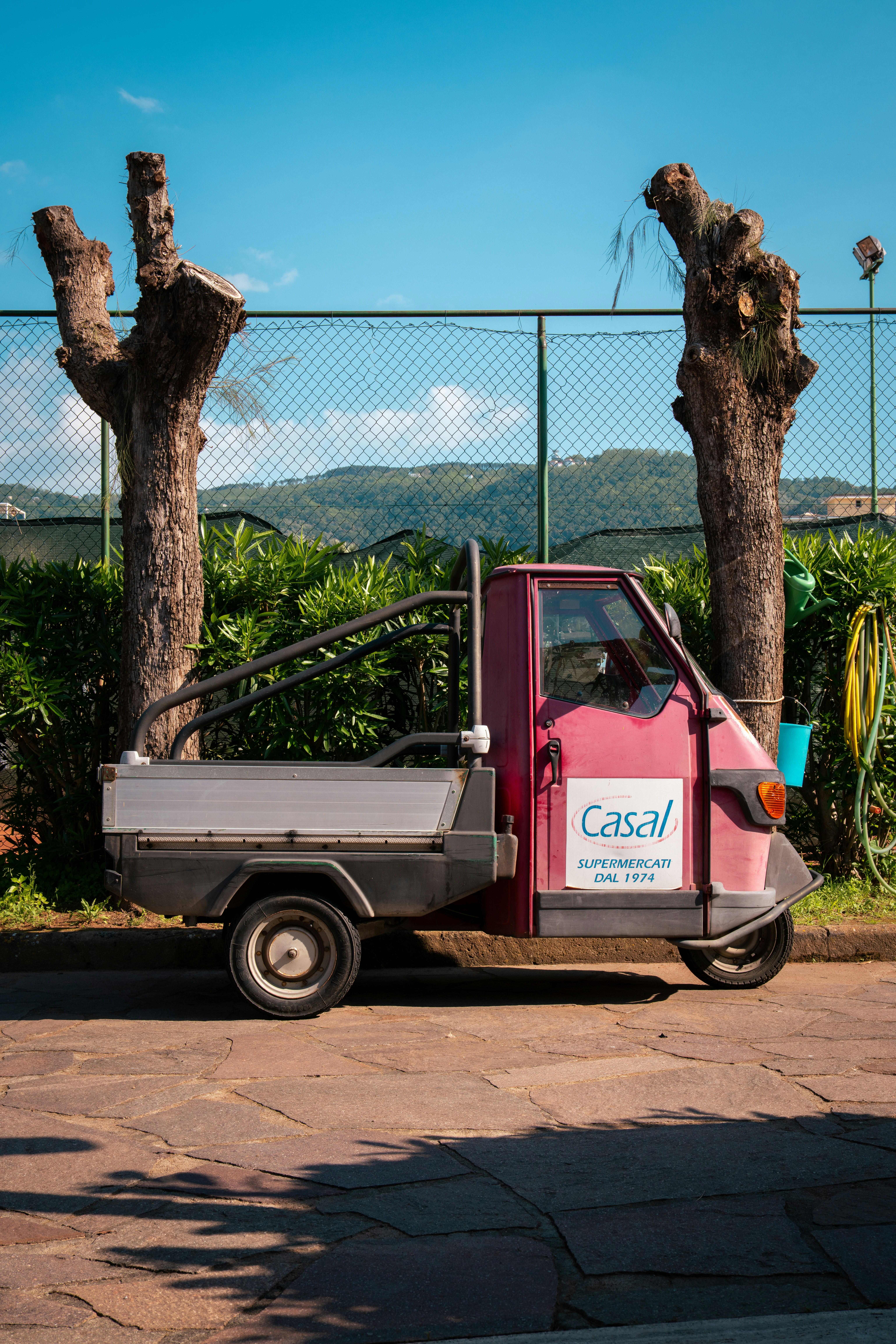 A pink truck parked in front of a fence