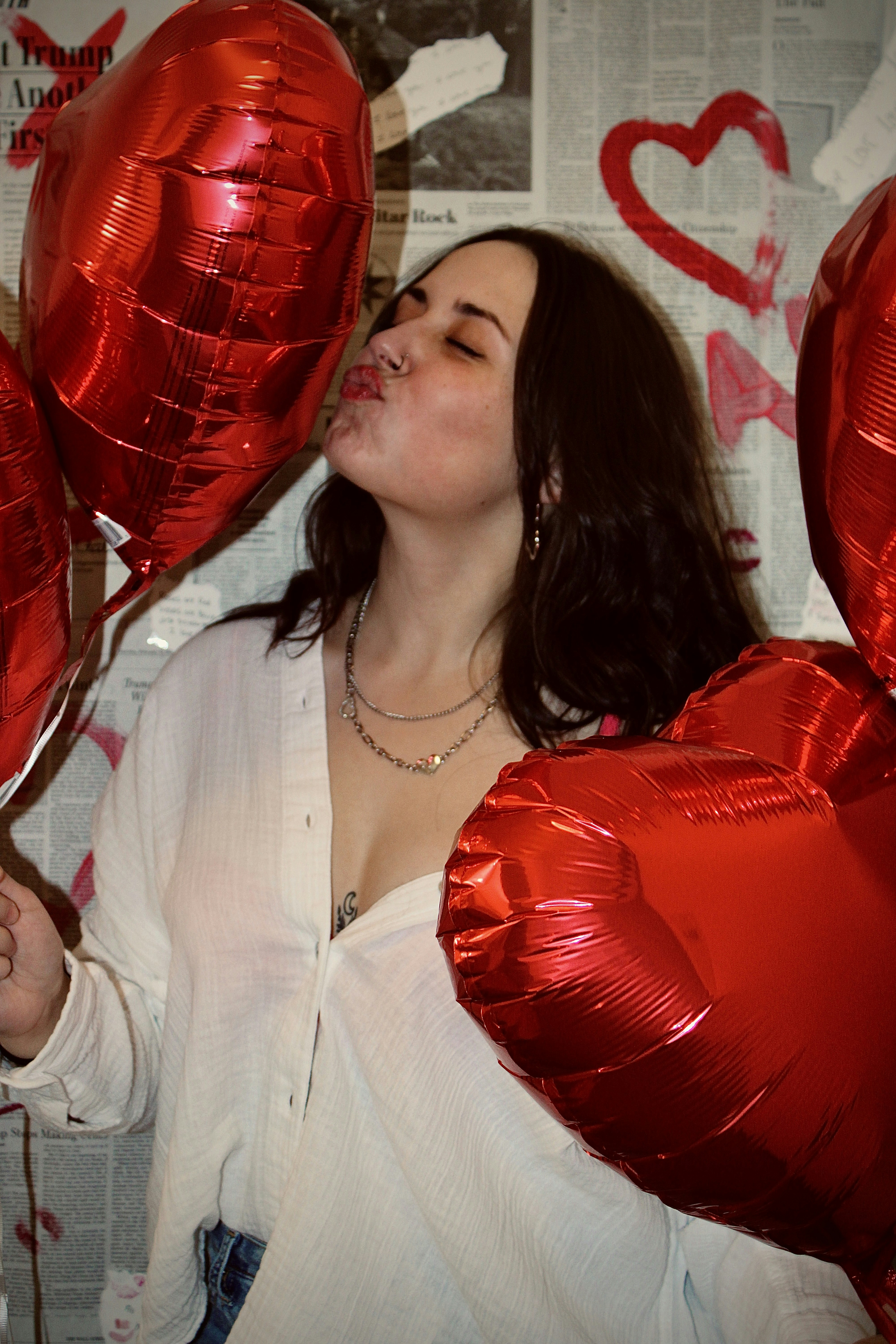 A woman holding red heart shaped balloons in her hands