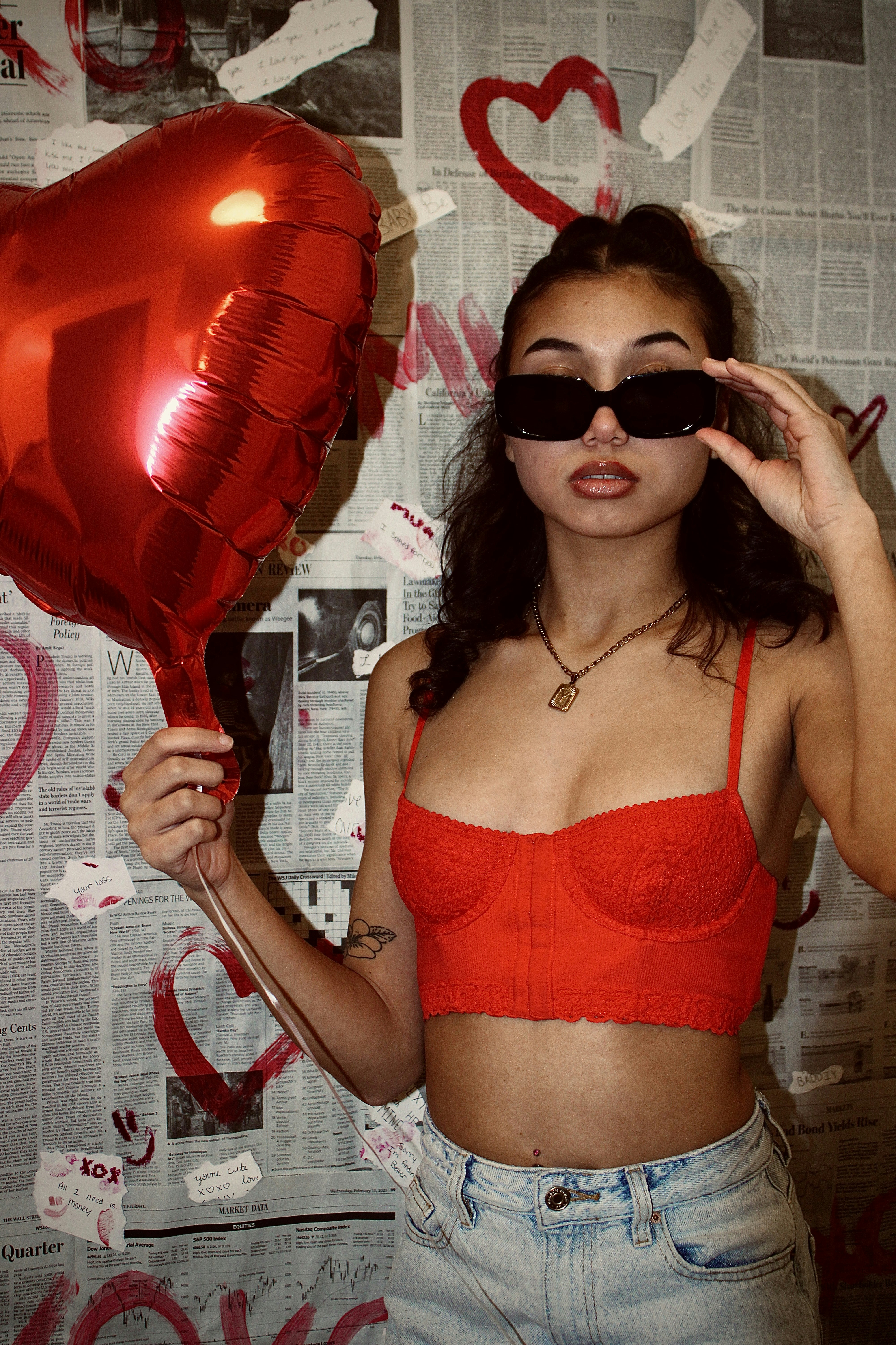 A woman holding a heart shaped balloon in front of a wall