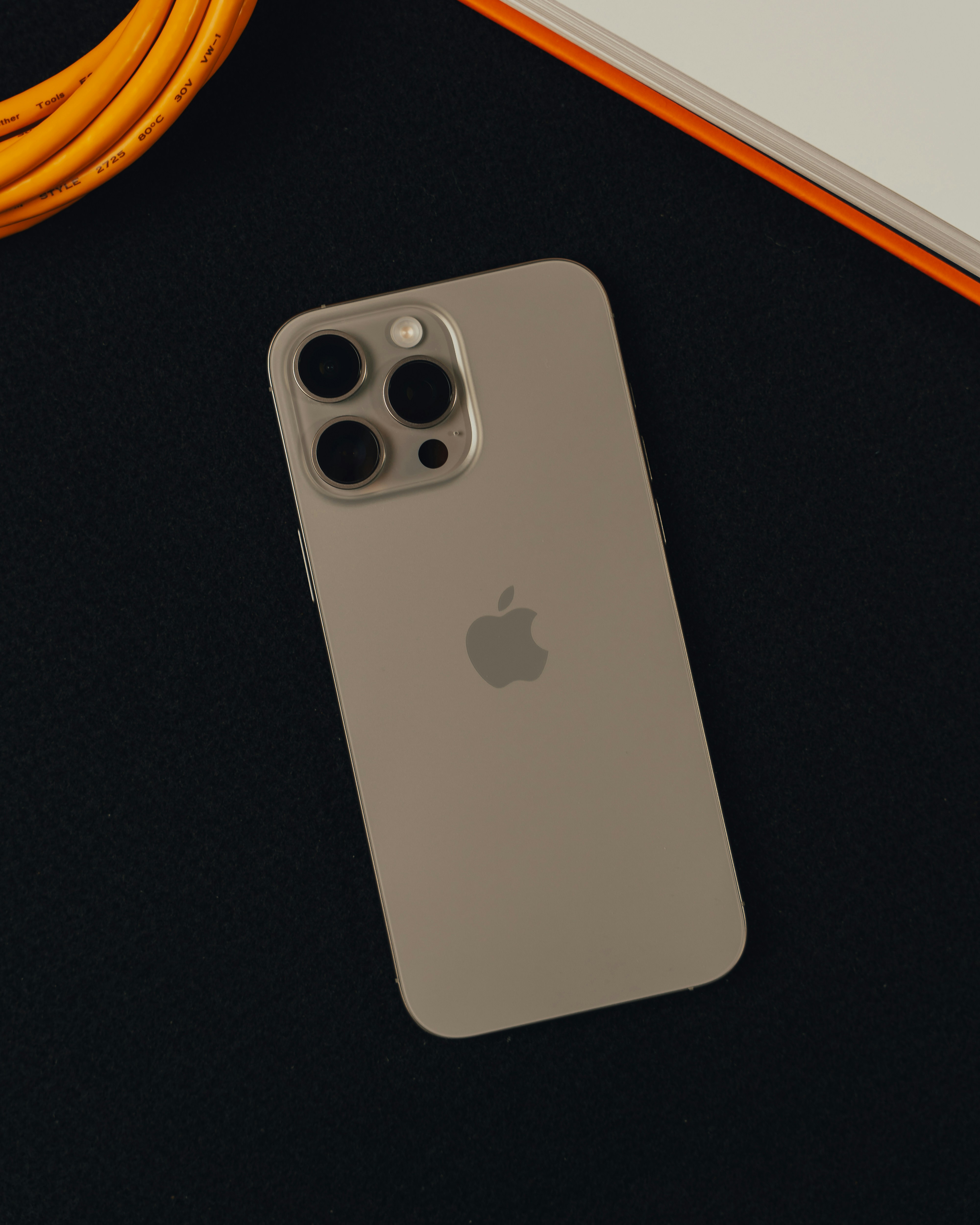 An apple phone sitting on top of a table next to a charger