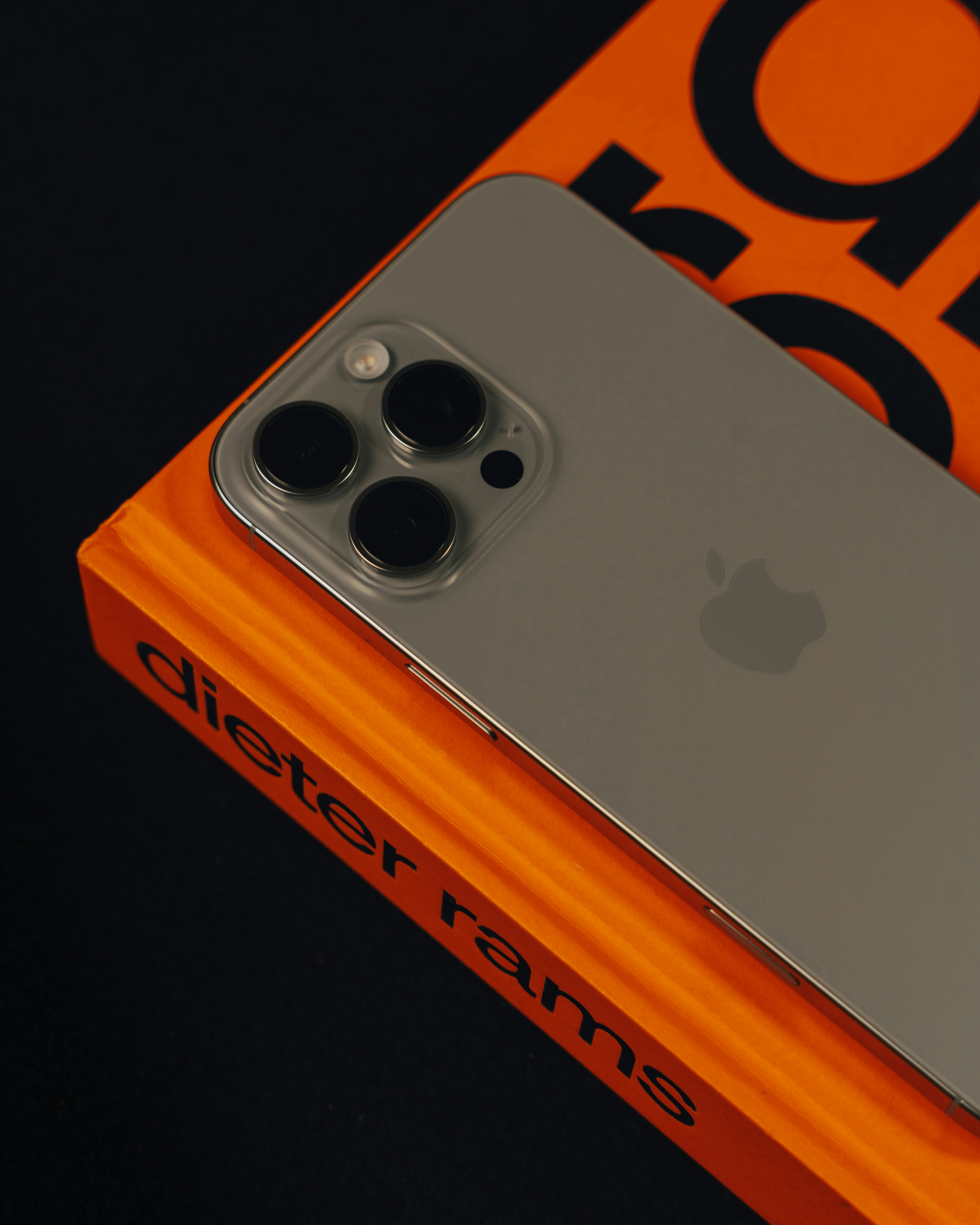 A silver and orange iPhone sitting on top of an orange box
