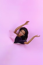 A doll is sitting on a pink surface