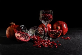 A glass of wine and some pomegranates on a table