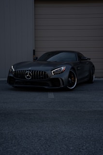 A black car parked in front of a garage door