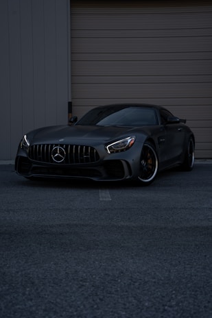 A black car parked in front of a garage door