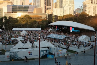 A crowd of people standing around tents in a city