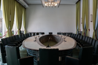 A conference room with a round table and black chairs