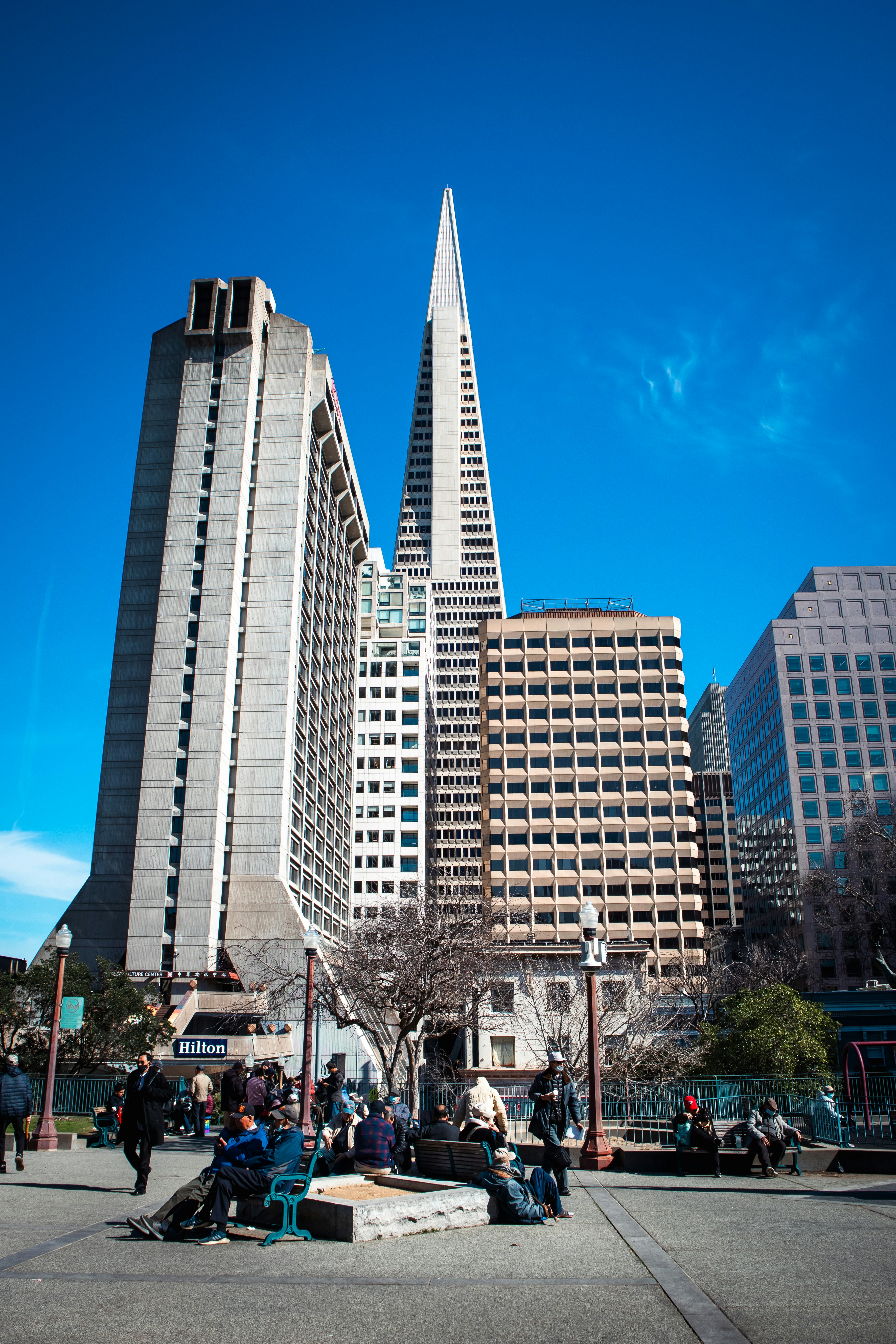 A group of people sitting on a bench in front of tall buildings