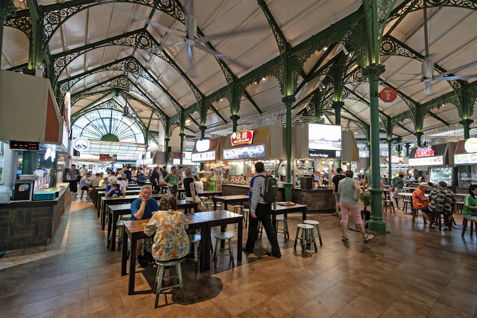People dining at communal tables inside a Singapore hawker centre