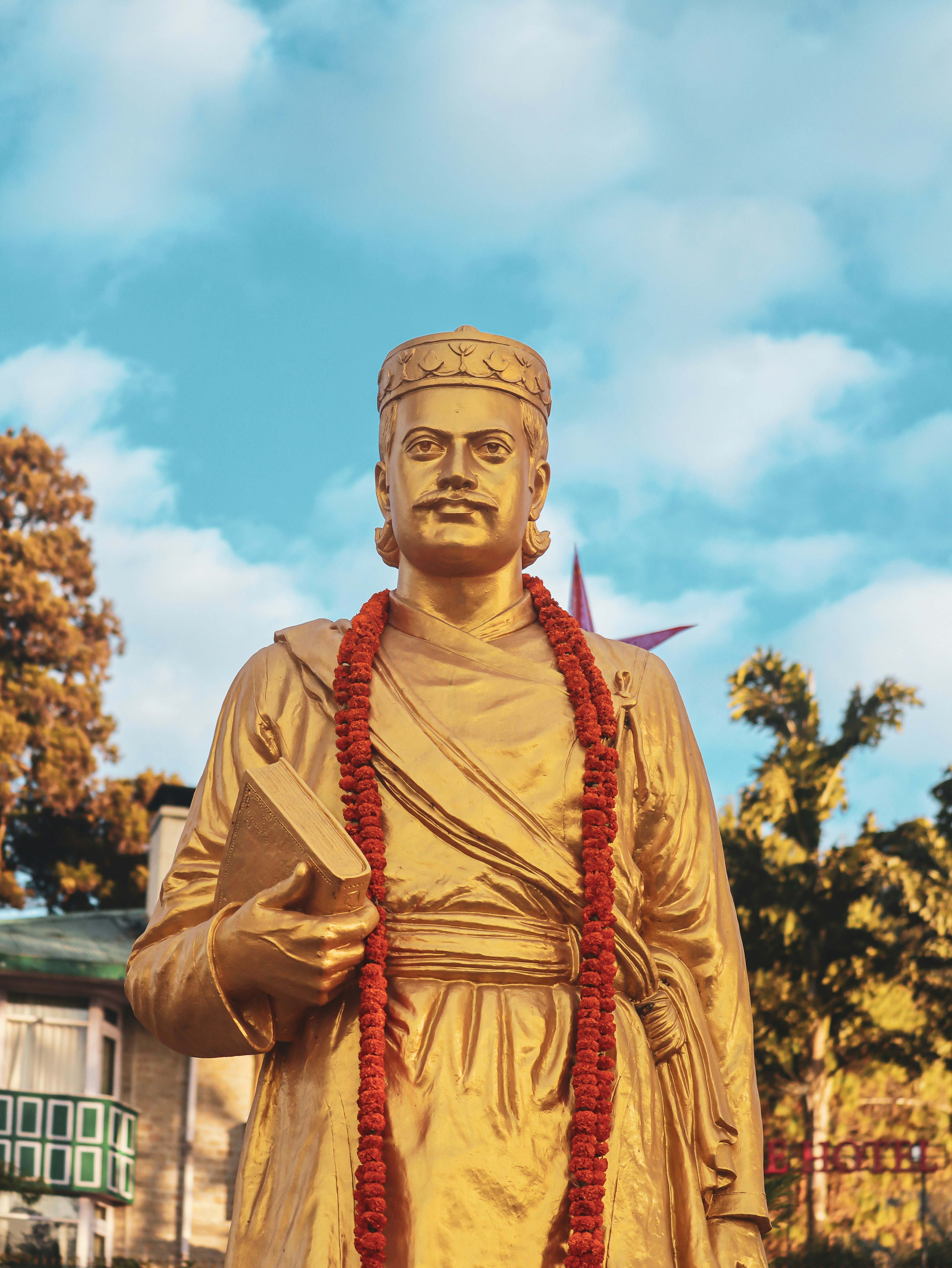 A golden statue of a man with a red lei around his neck