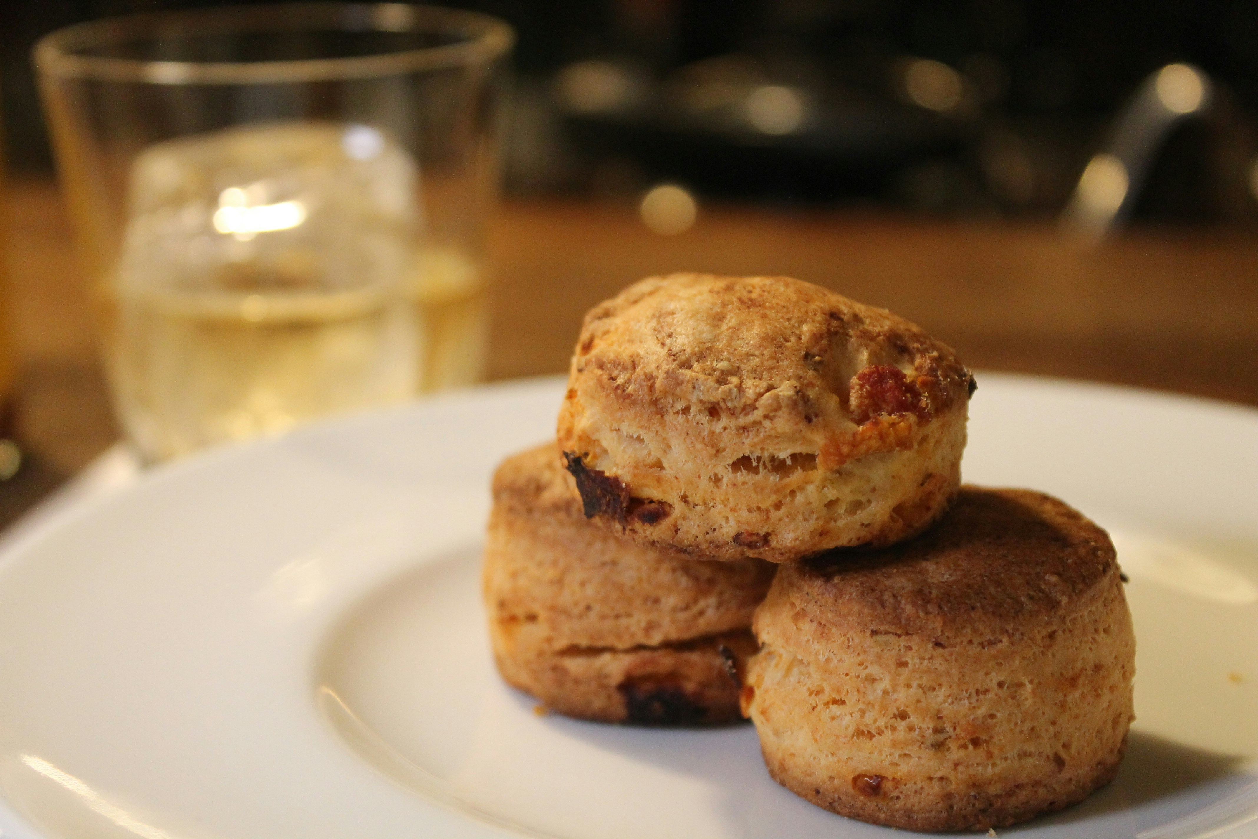A white plate topped with three cookies next to a glass of wine