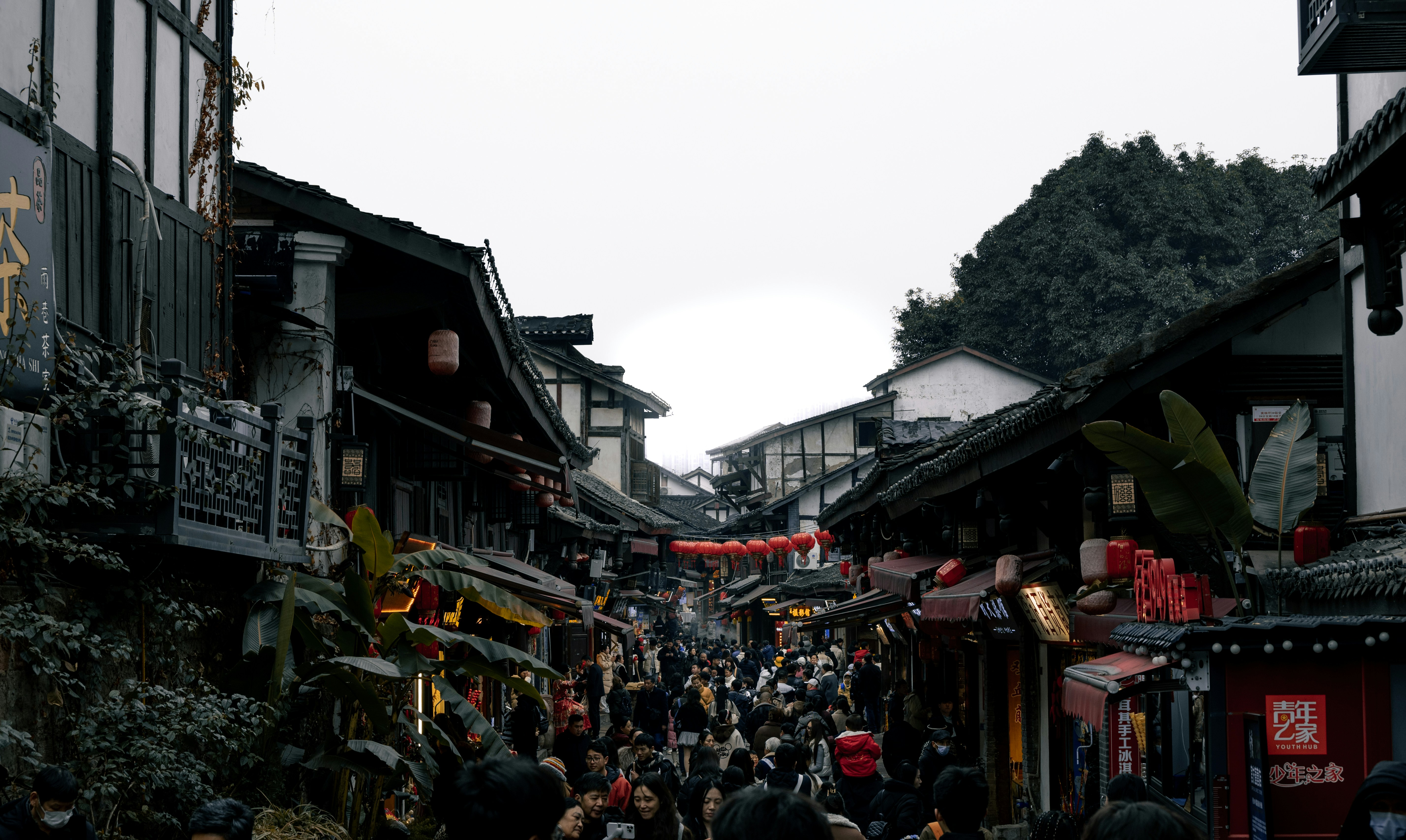 A group of people walking down a street next to tall buildings