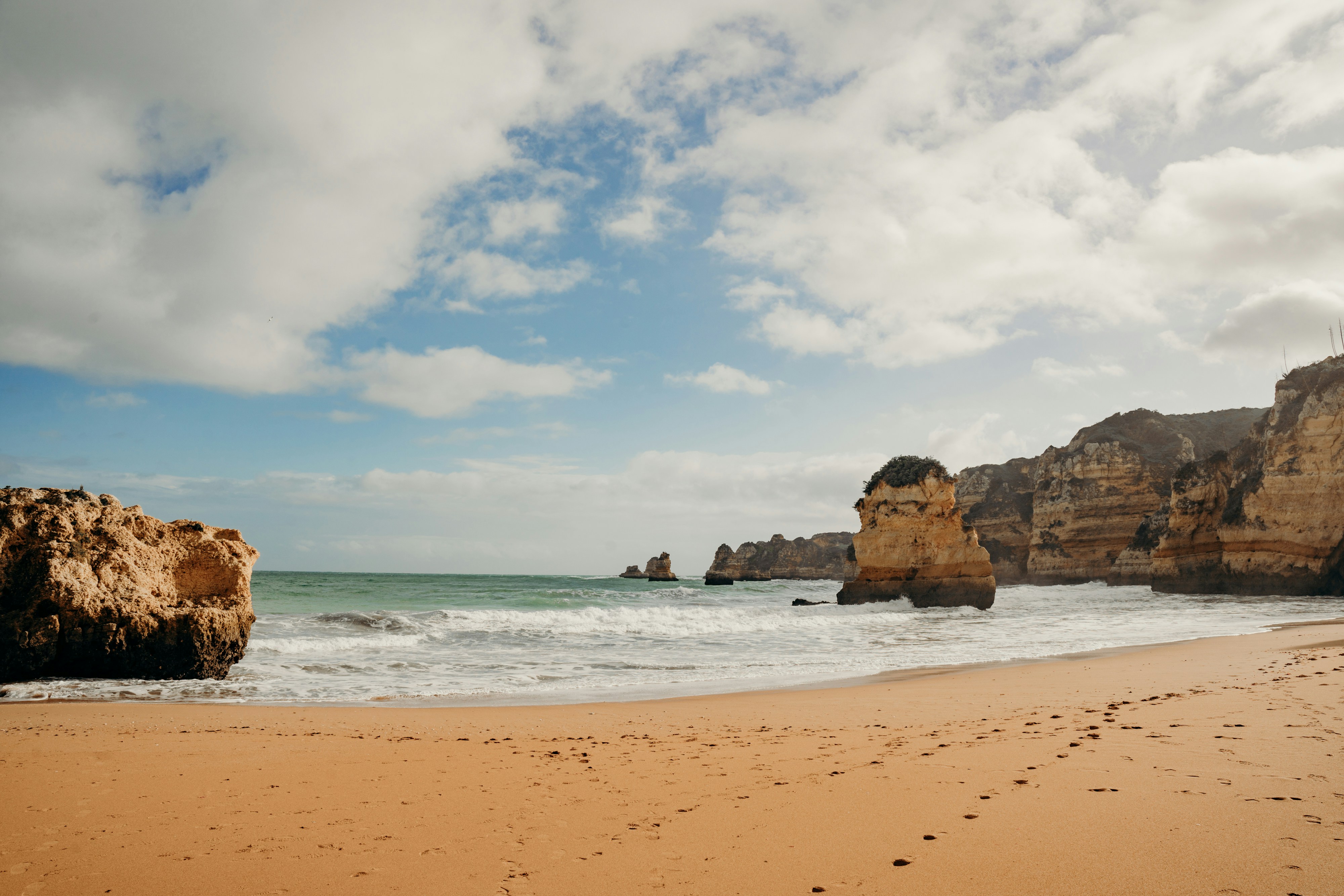 A sandy beach with a rock formation in the background