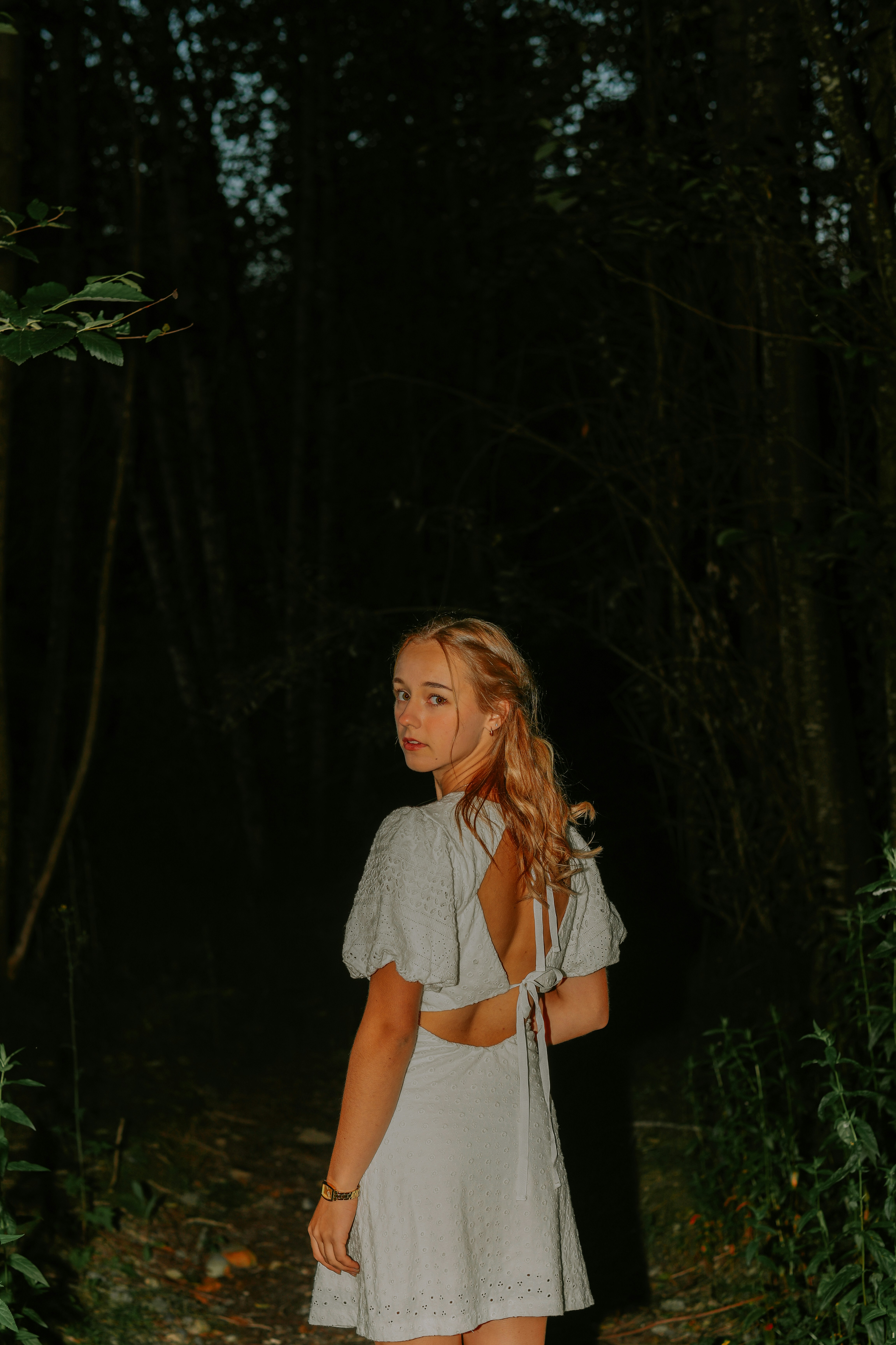 A woman standing in the woods at night