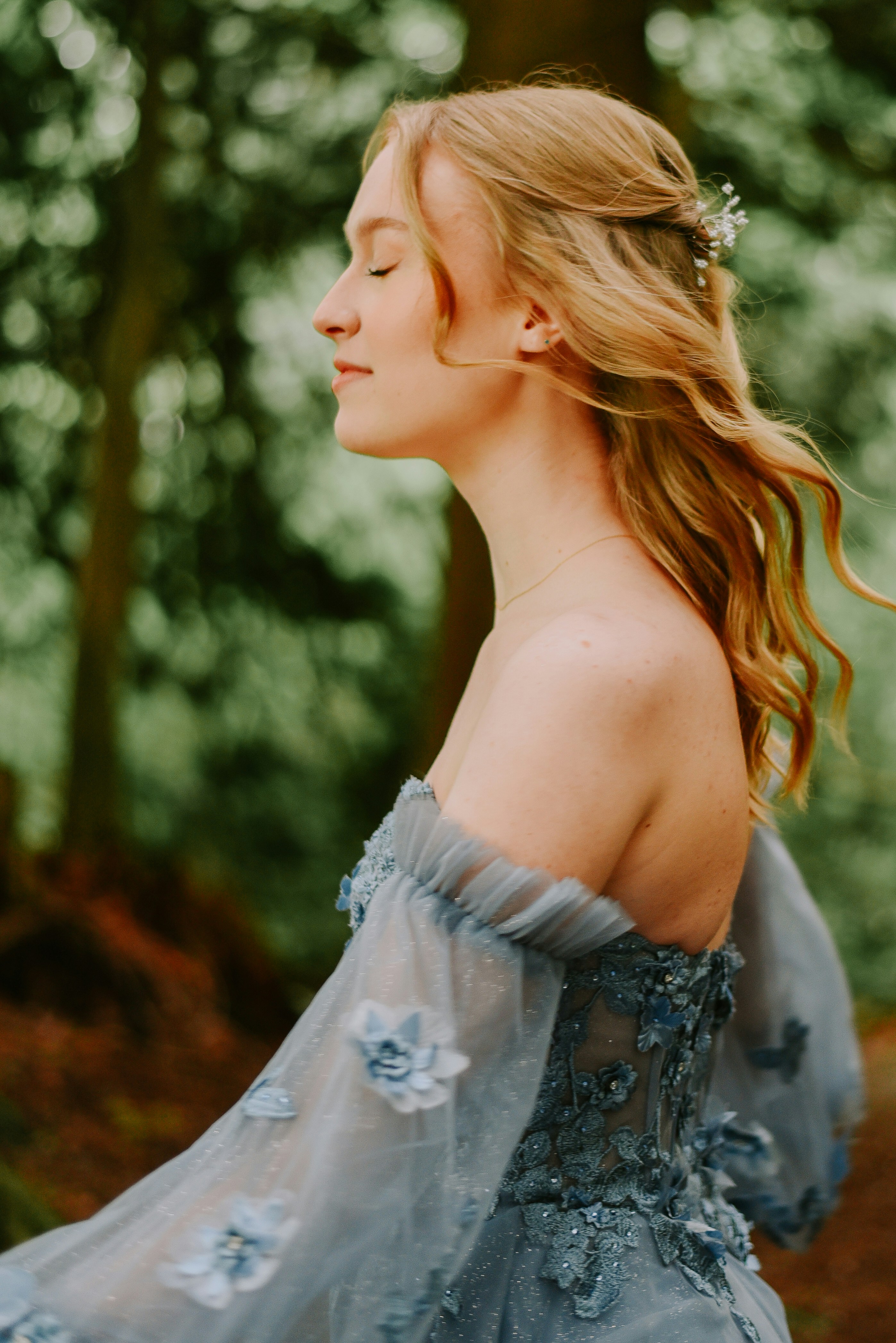 A woman in a blue dress standing in the woods