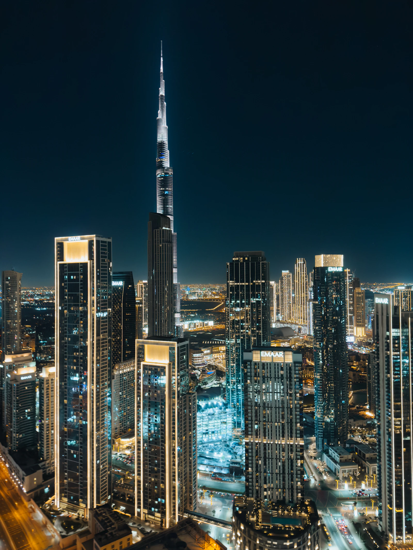 Dubai at night seen from above, towers lit against the dark