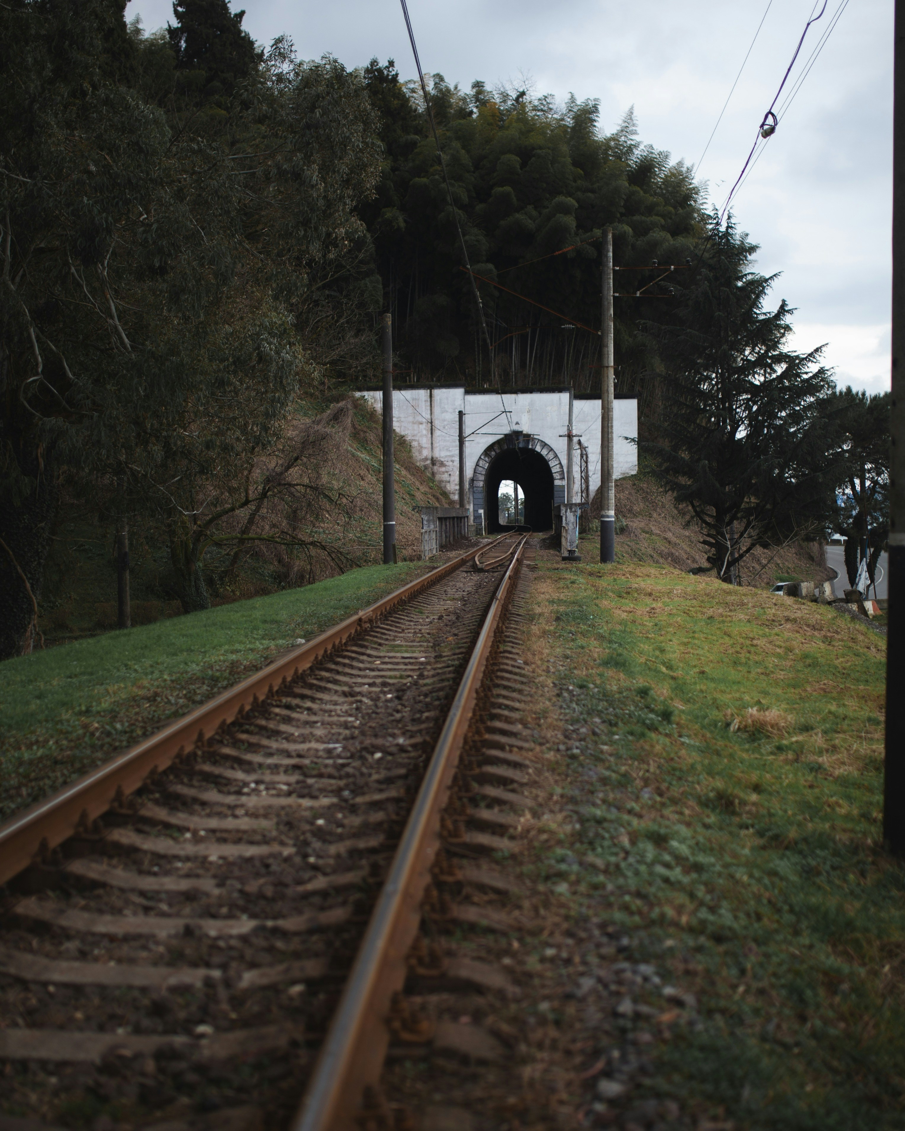 A train track going into a tunnel on a cloudy day