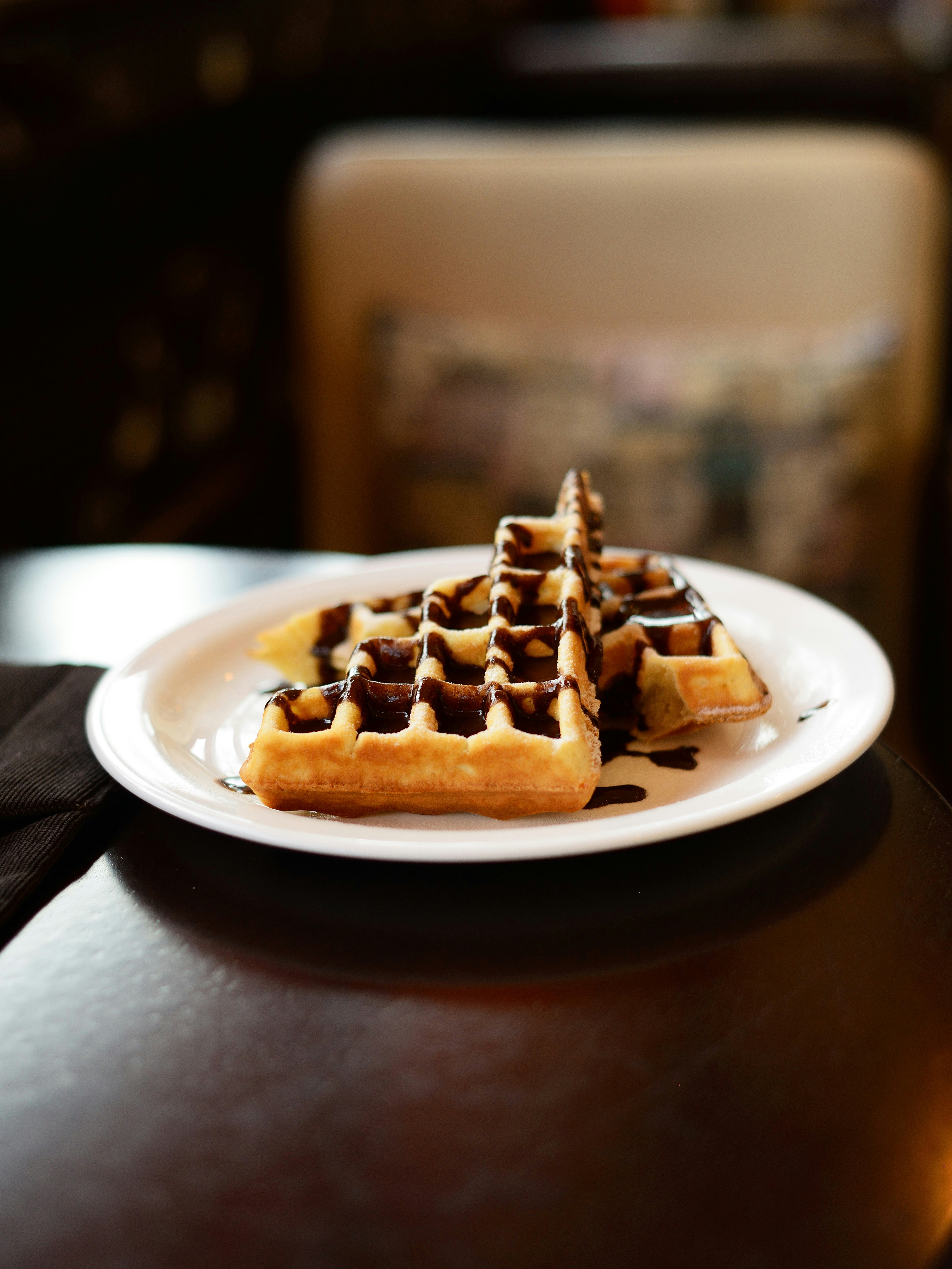 A white plate topped with waffles on top of a wooden table