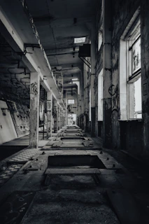 A long hallway with lots of windows and graffiti on the walls