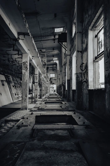 A long hallway with lots of windows and graffiti on the walls