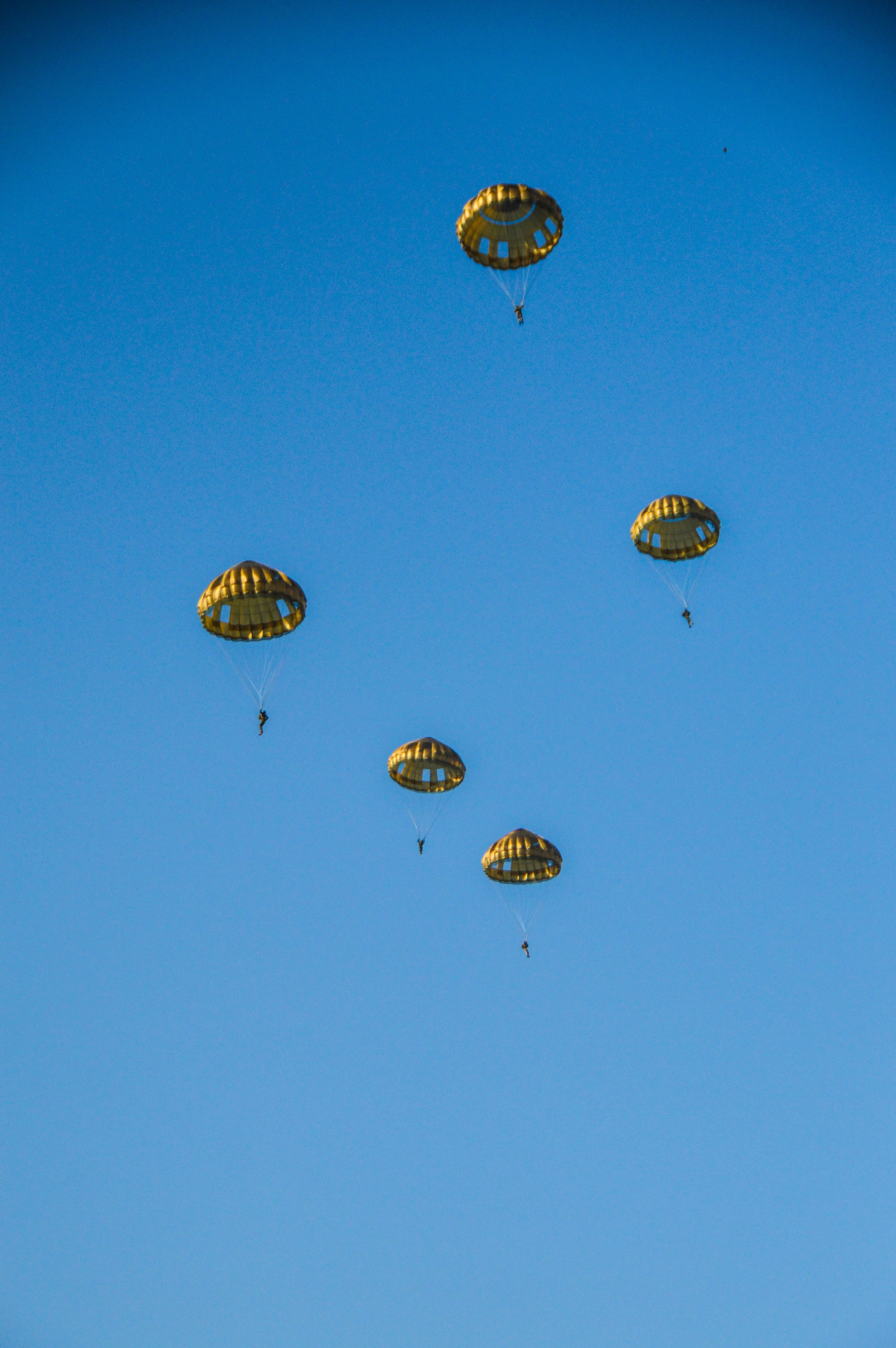 A group of parachutes flying through a blue sky