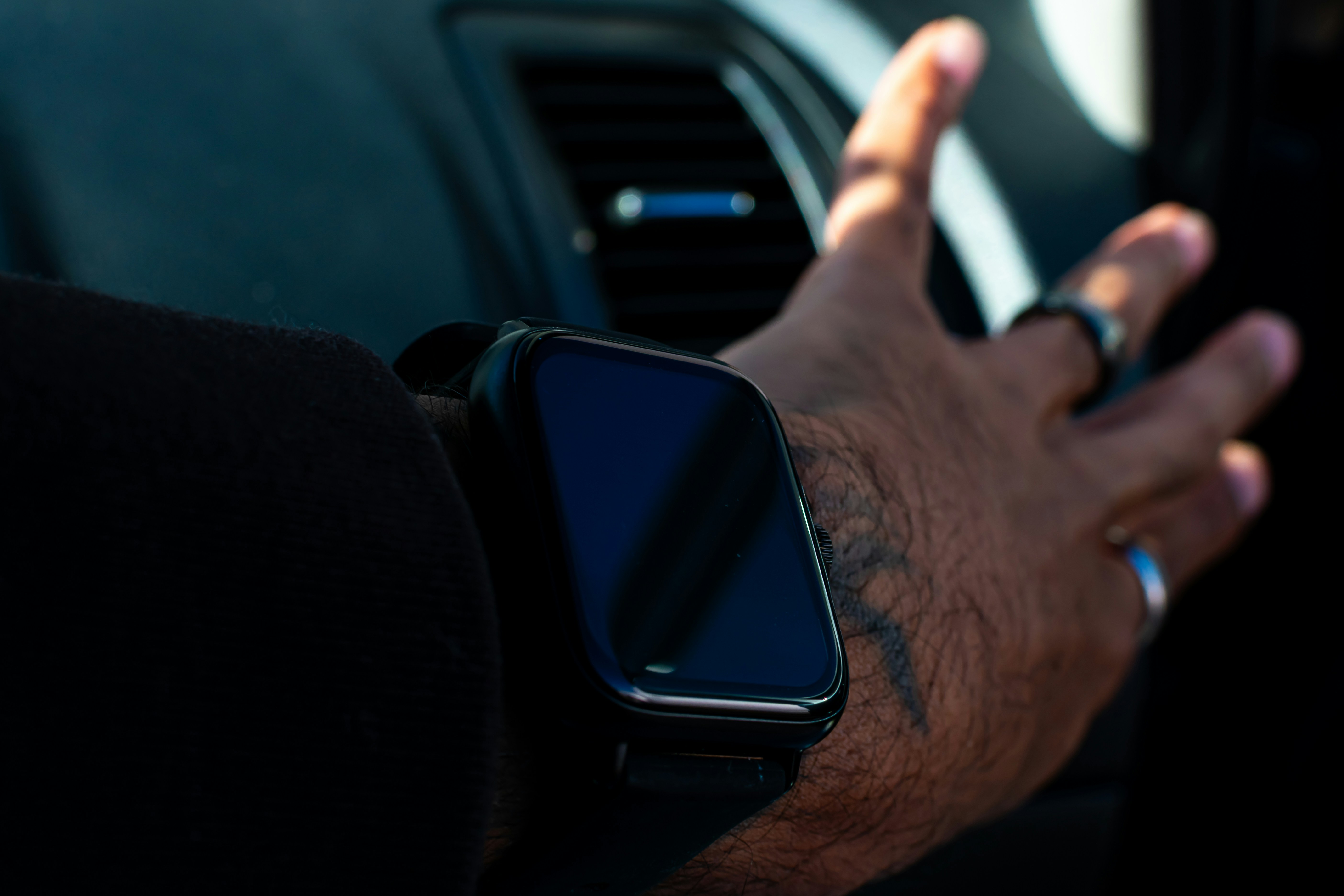 A man driving a car while holding a cell phone