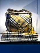 A burberst purse sitting on top of a stack of books