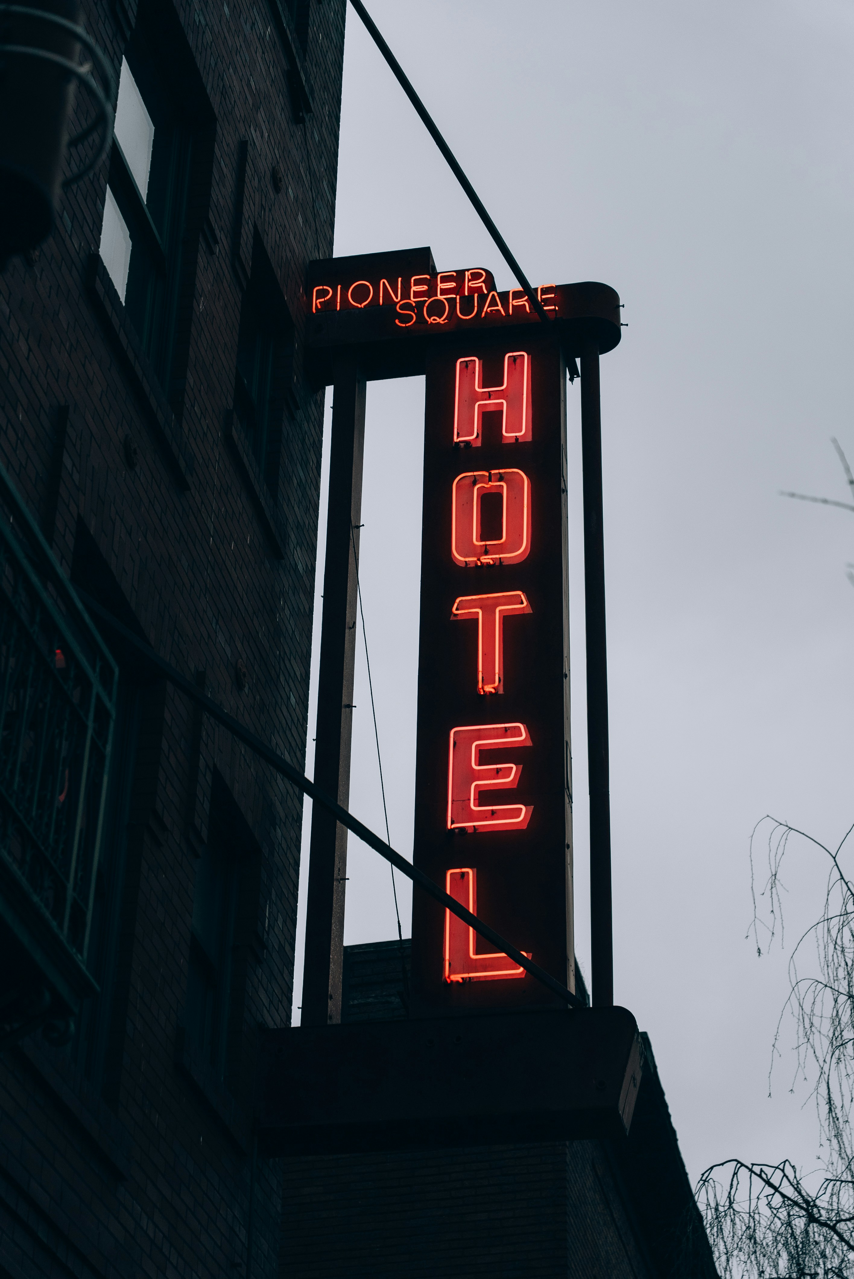 A neon hotel sign hanging from the side of a building